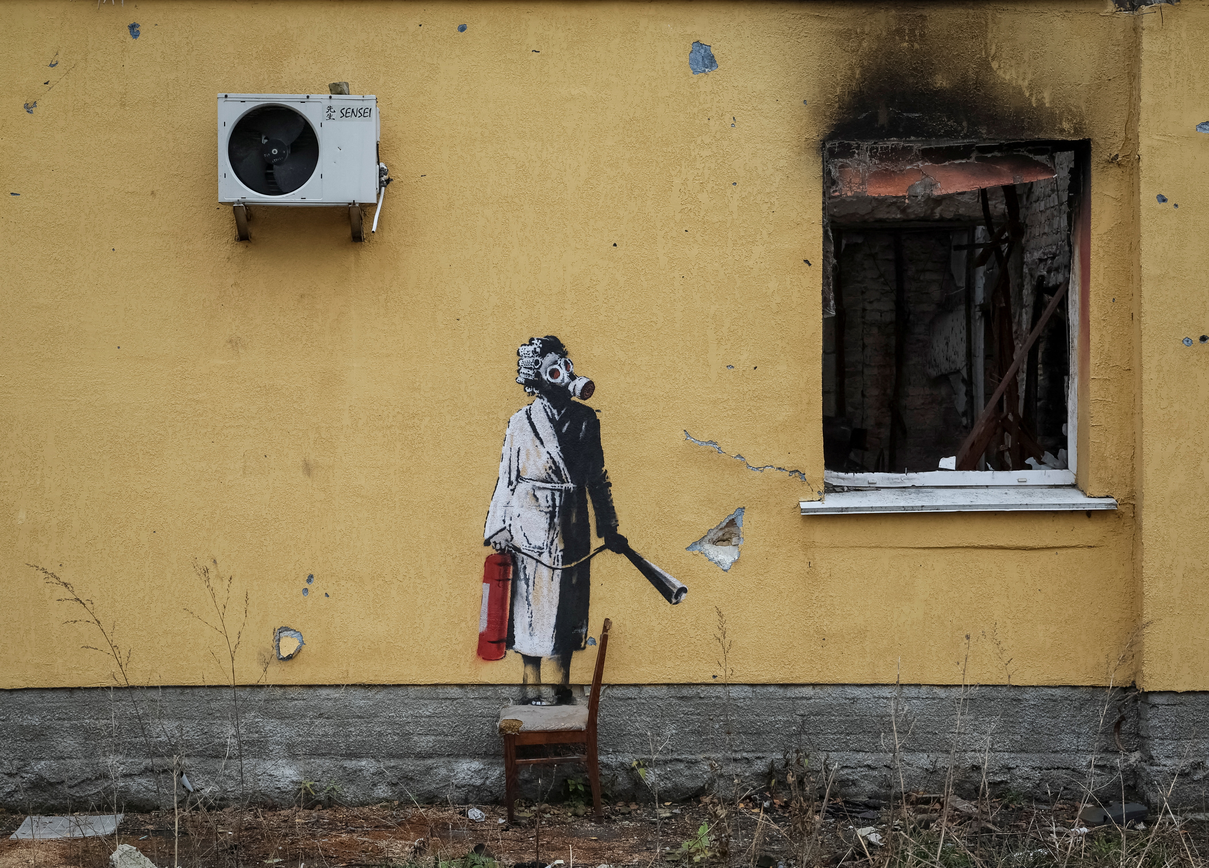 a woman in a gas mask and dressing gown holding a fire extinguisher on the side of a scorched building.