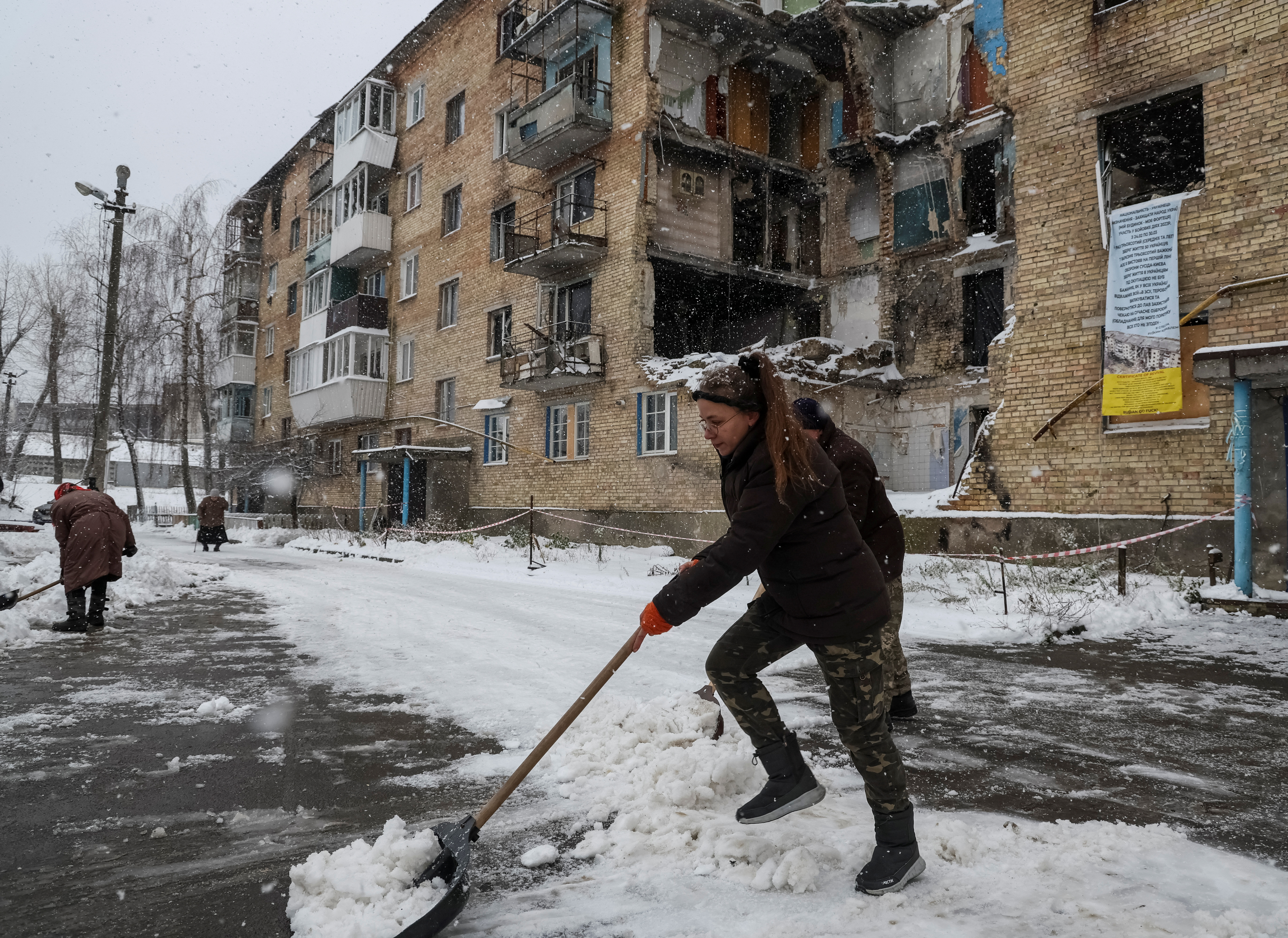 Resident Tetiana Reznychenko, 43, shovels snow near her destroyed building, which has no electricity, heating and water.
