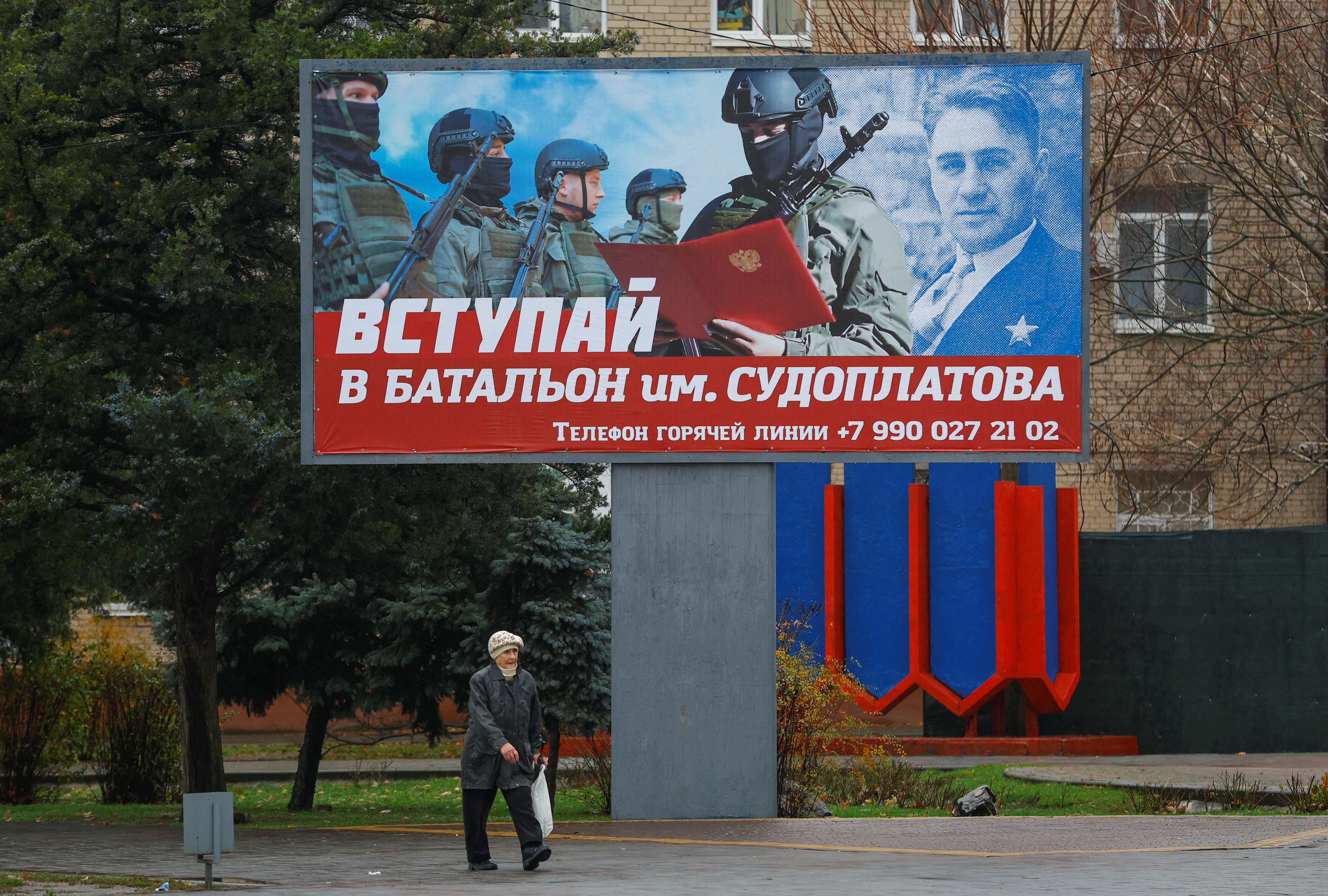 A local resident walks past a board encouraging to join a Russian army battalion in the course of Russia-Ukraine conflict in Melitopol, Russian-controlled Ukraine