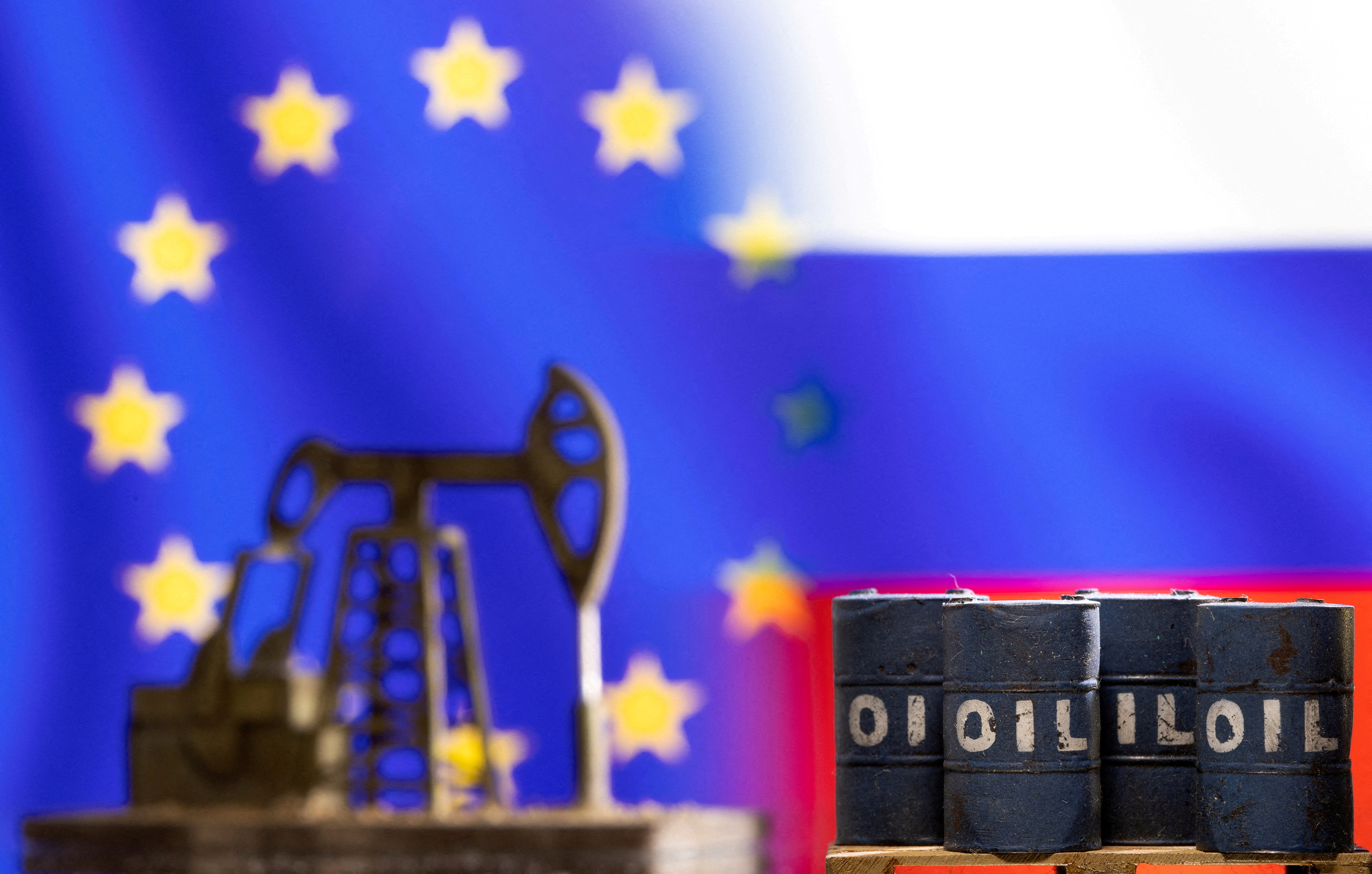 Models of oil barrels and a pump jack are seen in front of displayed EU and Russia flag colours
