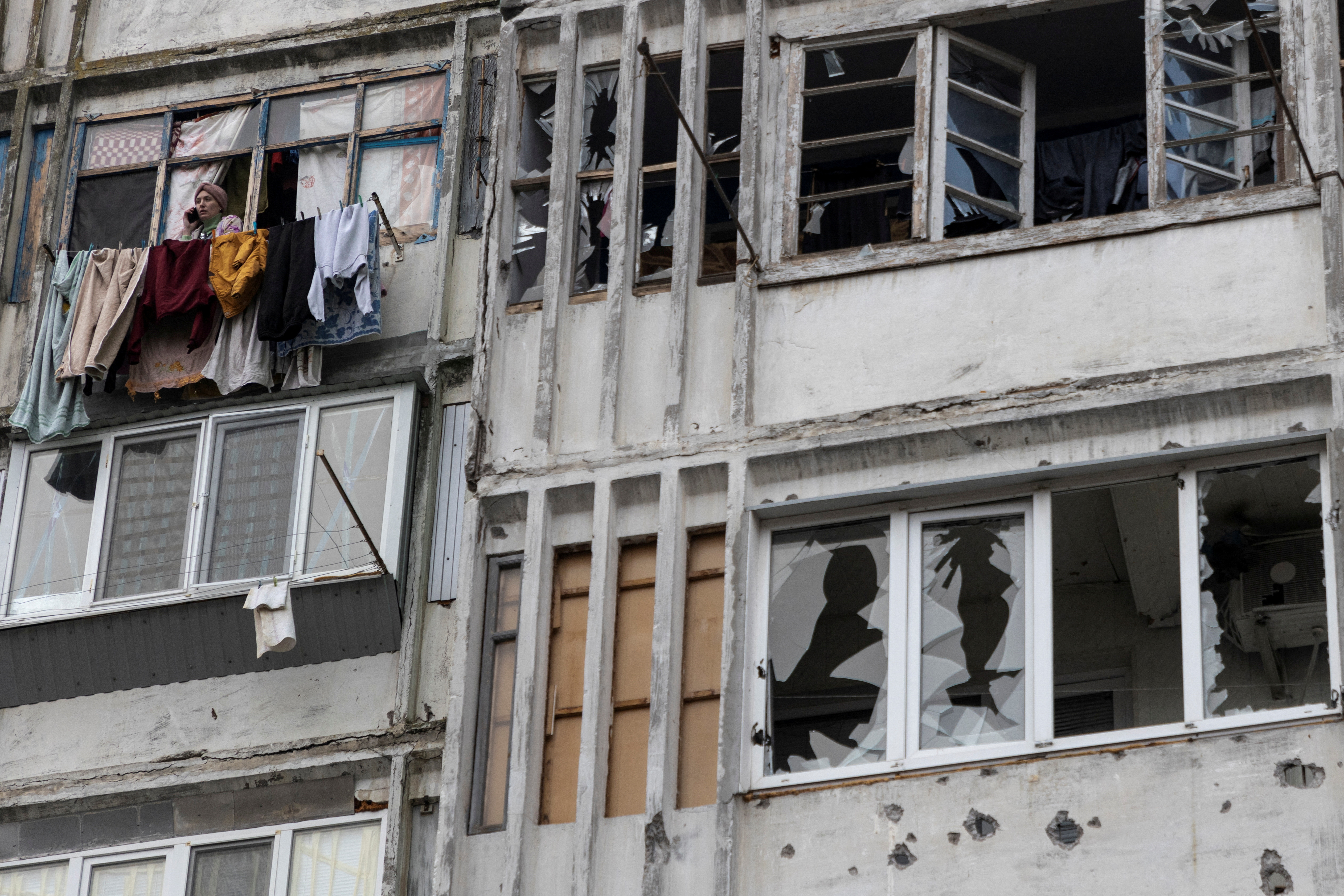 A local woman speaks on her mobile phone in a window of a residential building damaged by a Russian military strike, amid Russia's attack on Ukraine continues, in Kherson, Ukraine December 1, 2022. REUTERS/Anna Voitenko TPX IMAGES OF THE DAY