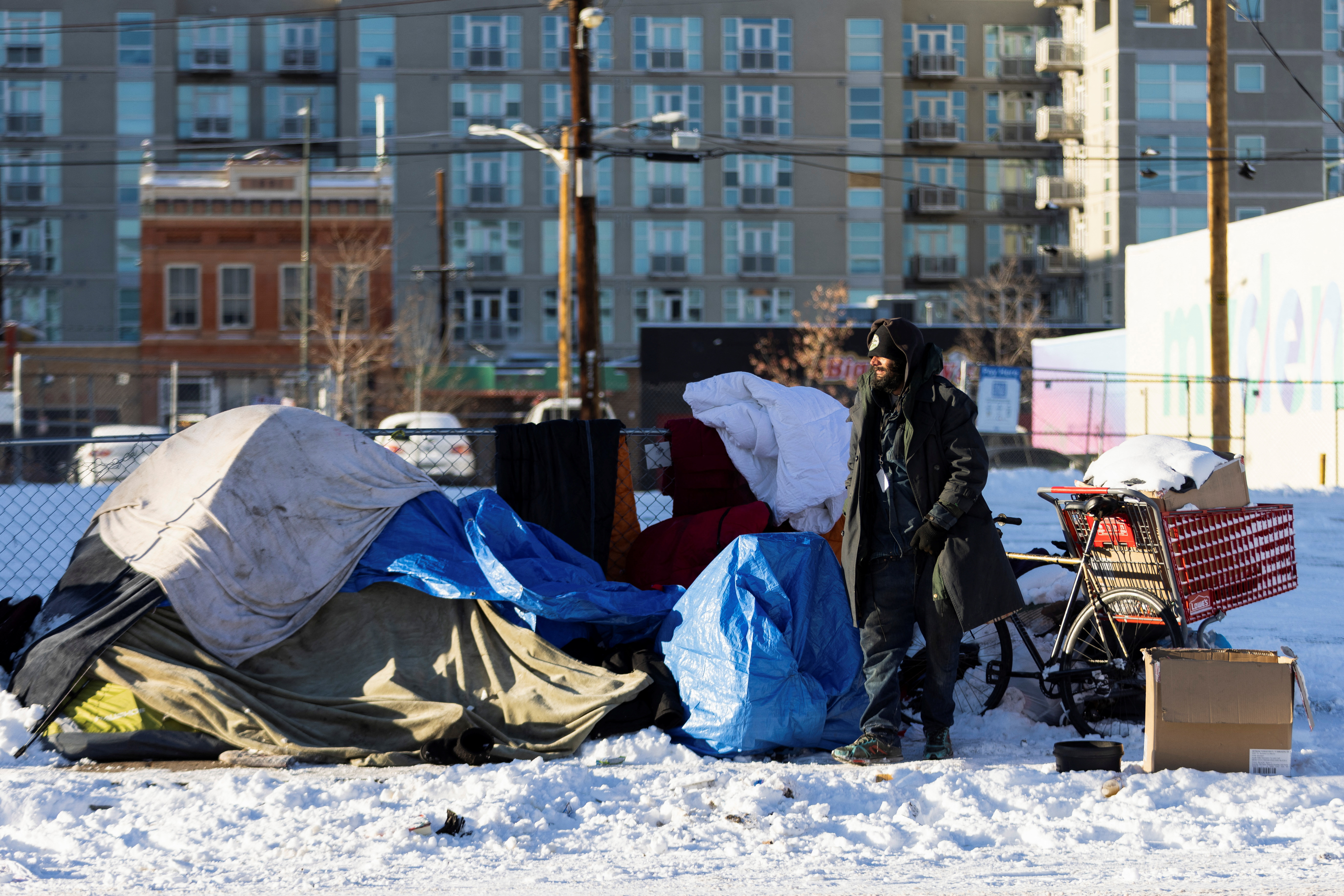 A man stands outside of his tent during a period of cold weather