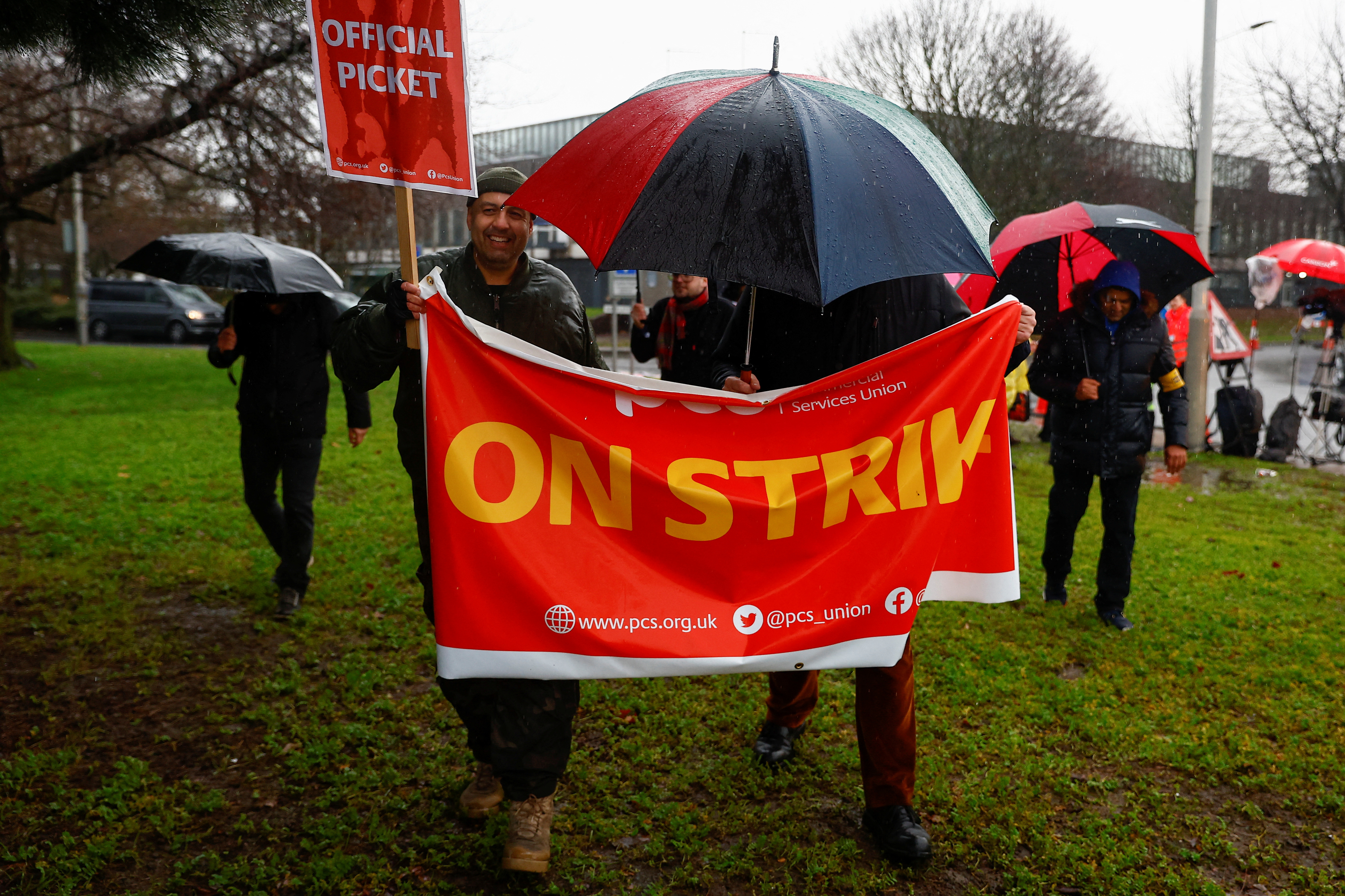 Members of the Public and Commercial Services (PCS) Union hold a banner, as they take part in a border force workers strike action near Heathrow Airport, in London, Britain December 23, 2022. REUTERS/Peter Nicholls