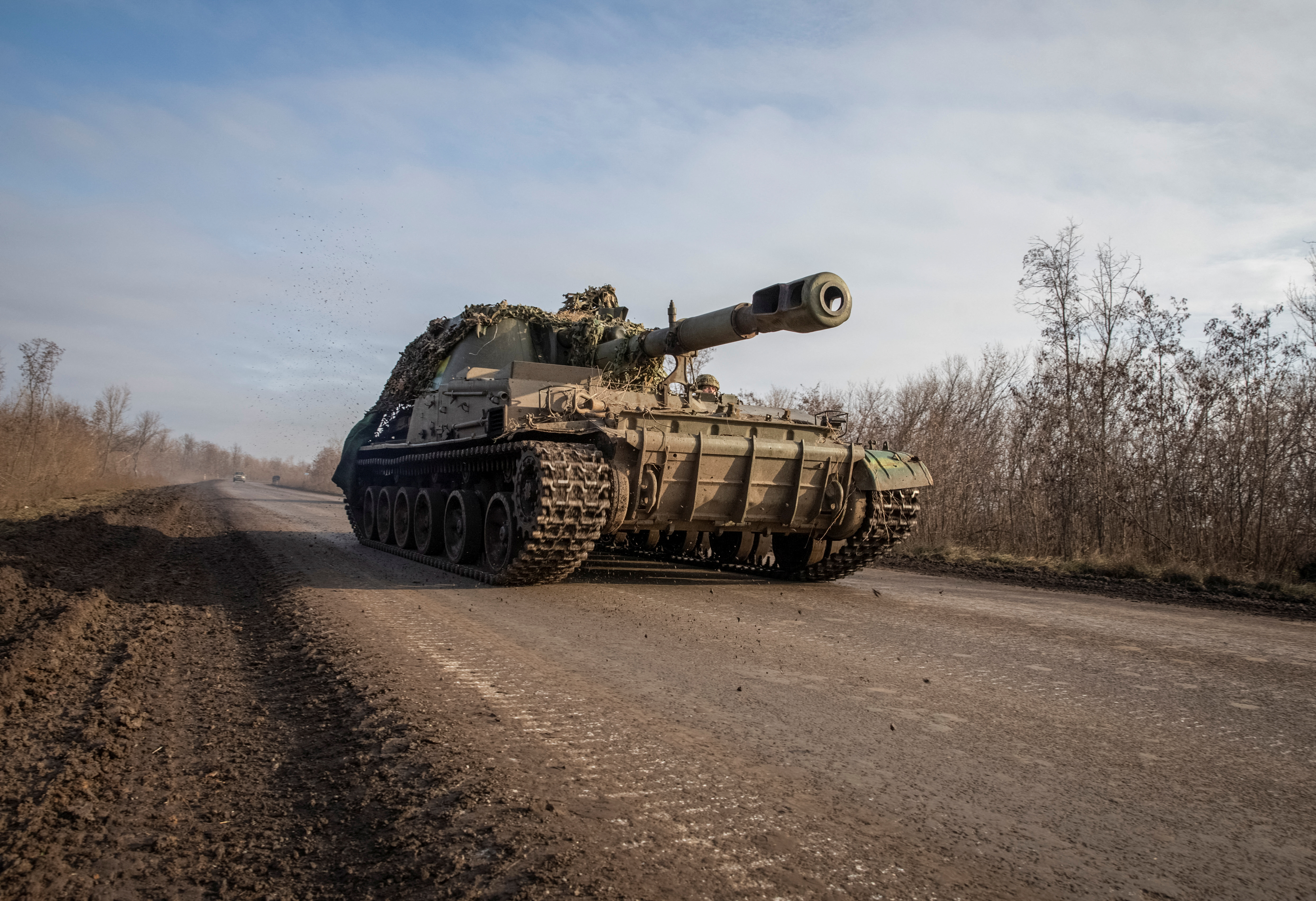 Ukrainian service members ride a self-propelled howitzer in eastern Ukraine.