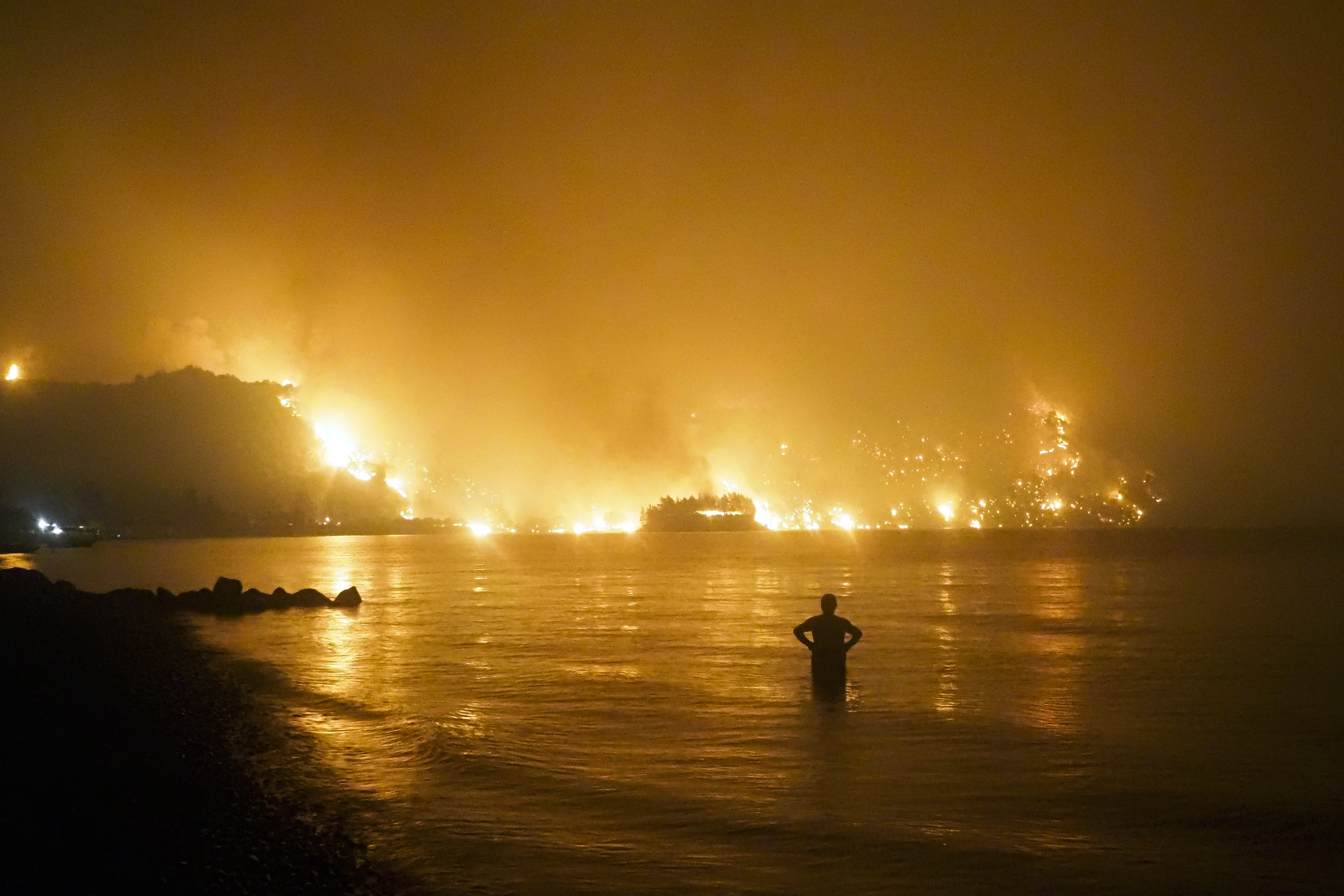 A man watches as a wildfire approaches Kochyli beach
