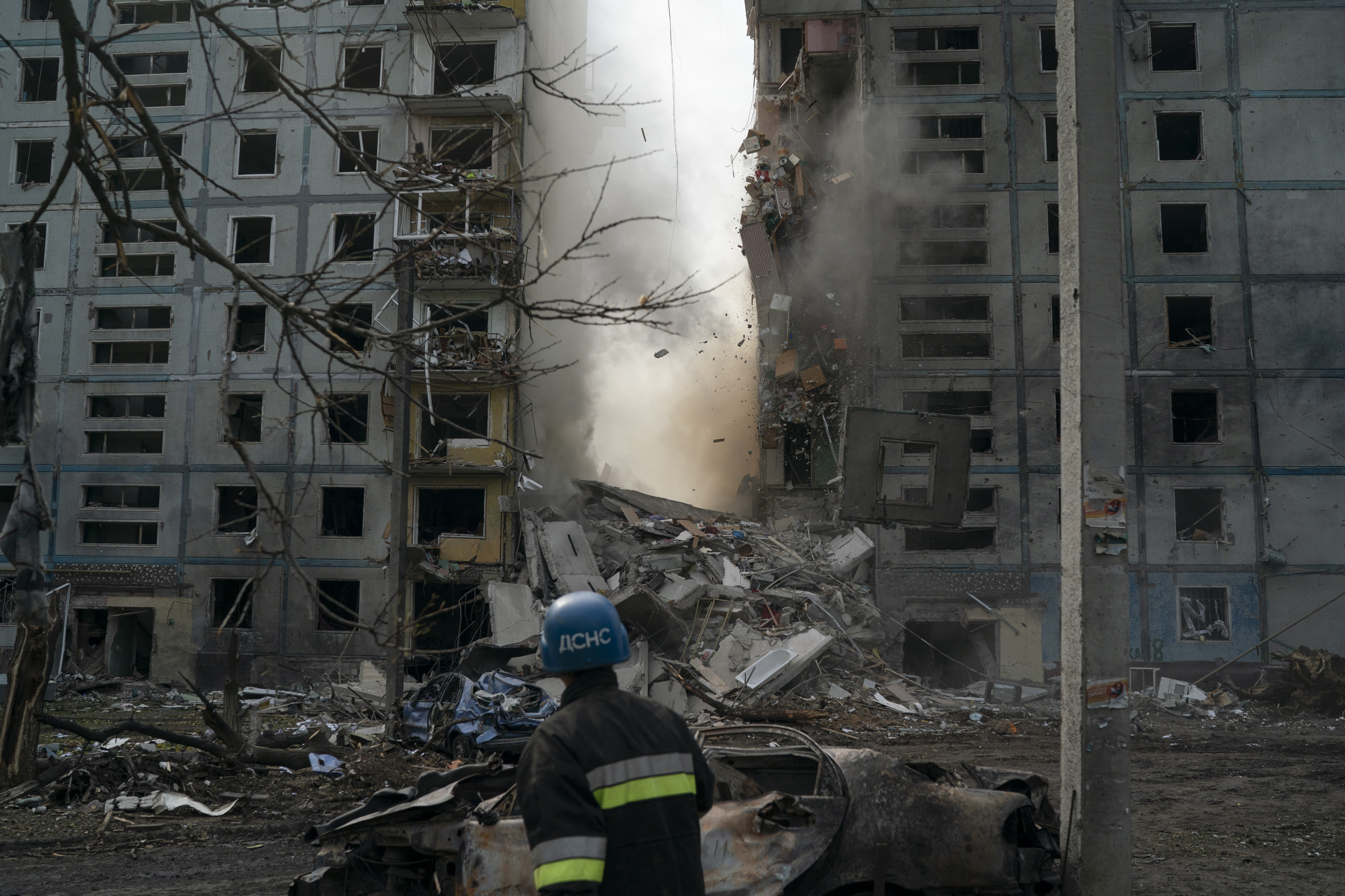 A firefighter looks at a part of a wall falling