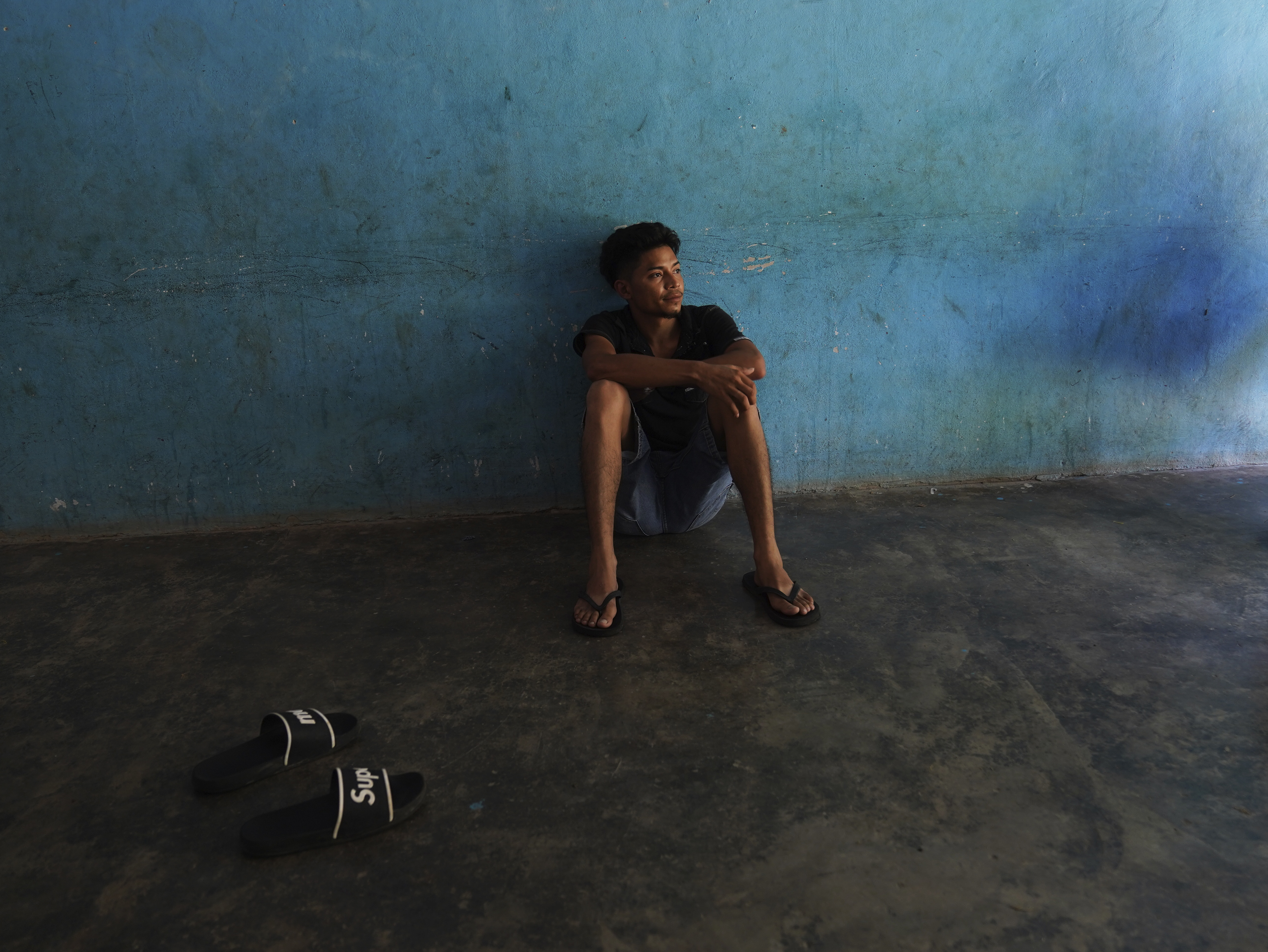 A migrant sits on the floor of a local's home where he is paying to stay