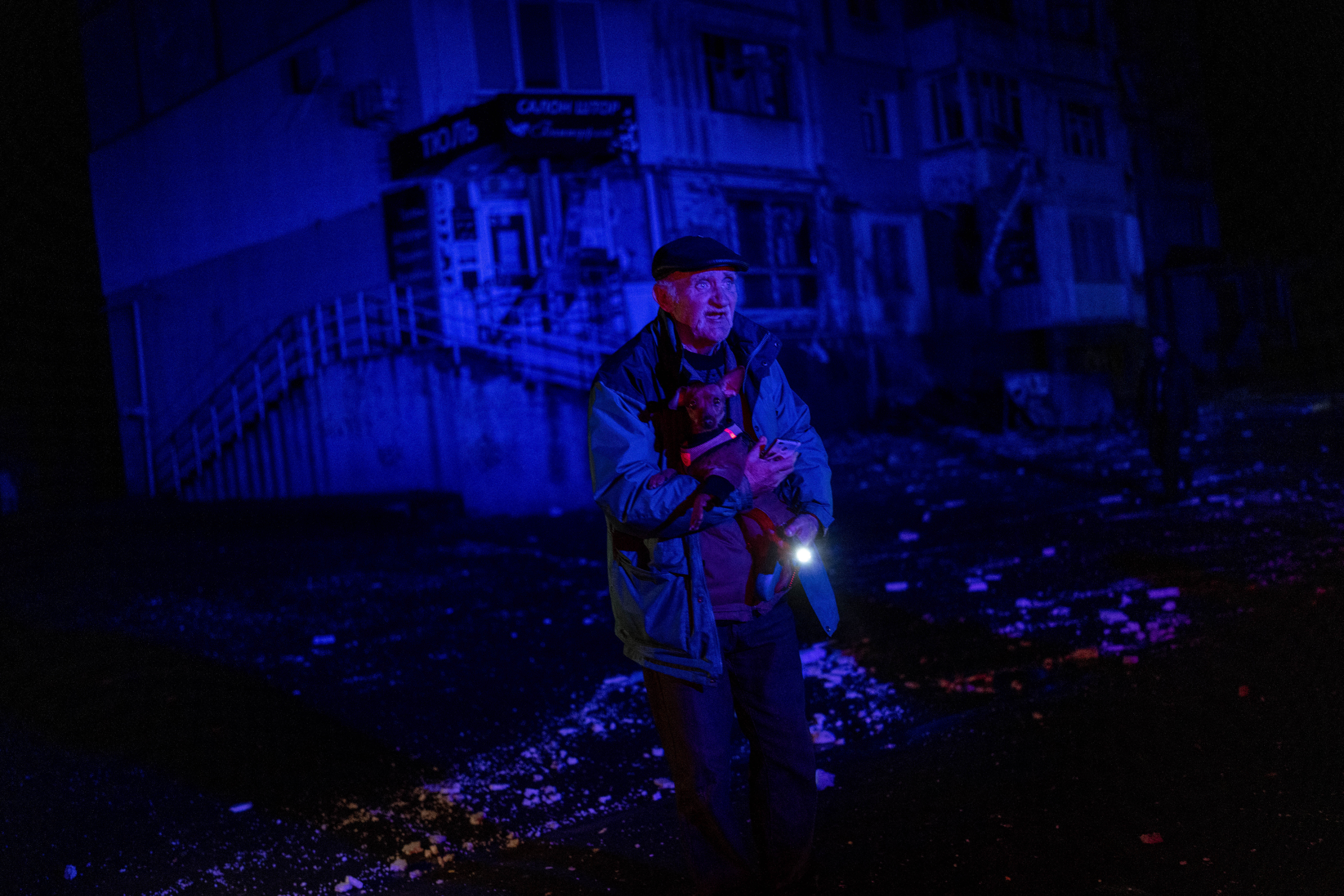 An elderly man holds a dog as he walks amid debris after a Russian attack in Kherson, southern Ukraine, Thursday, Nov. 24, 2022. (AP Photo/Bernat Armangue)