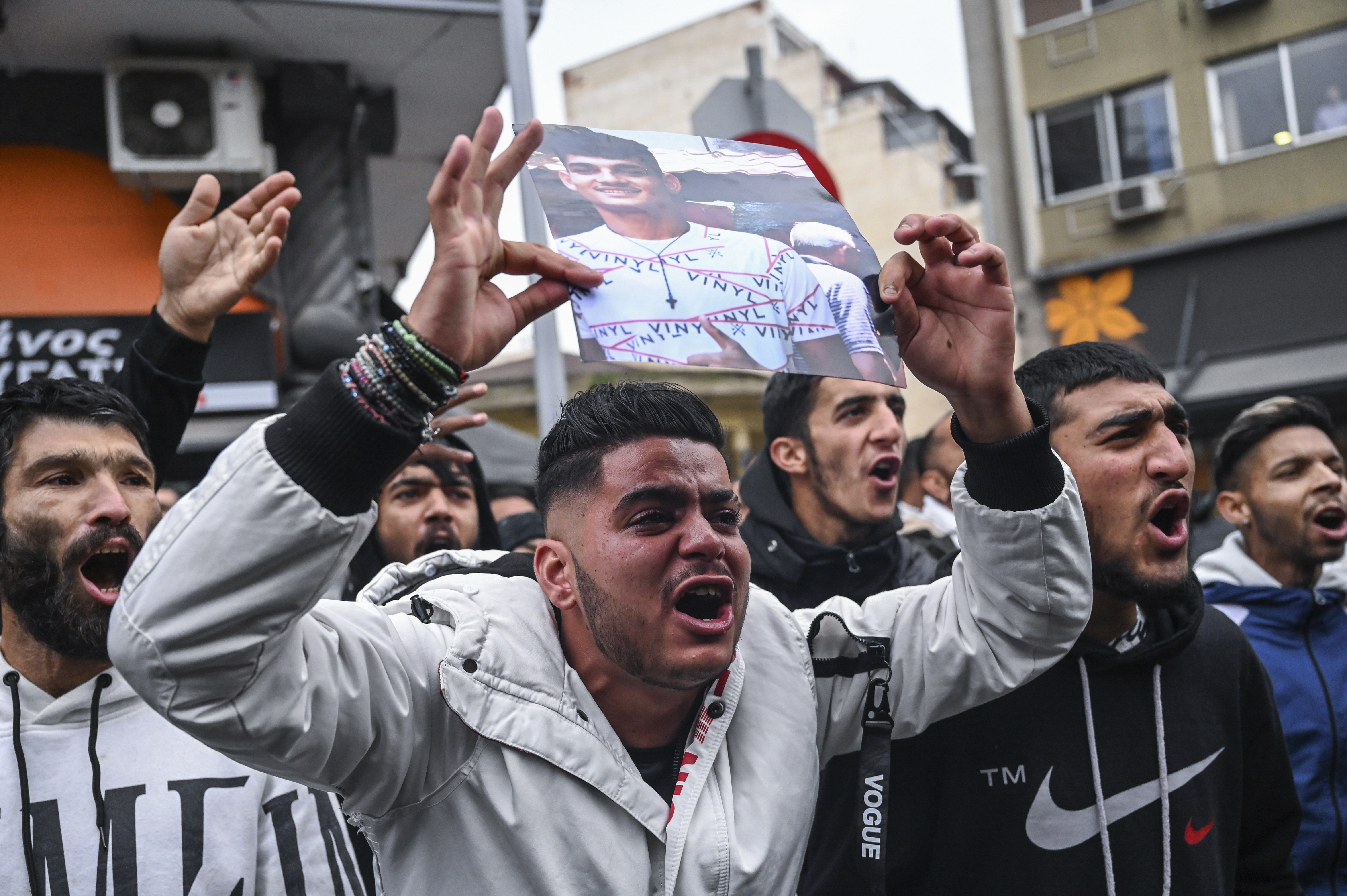 Relatives and other protesters from the Roma community chant slogans outside the courthouse in Greece's second largest city of Thessaloniki, holding up photos of an injured 16-year-old and calling for justice