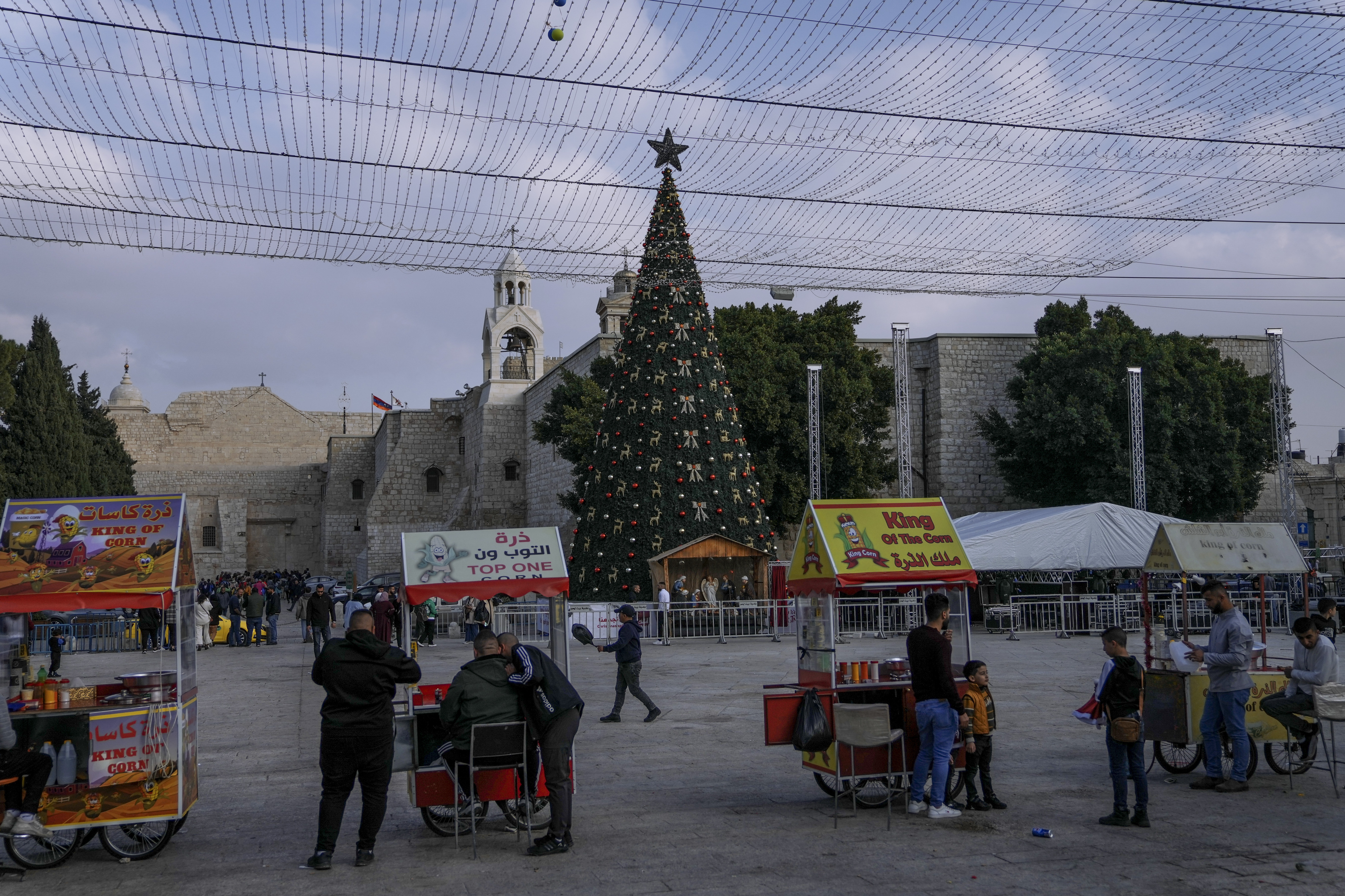 Palestinian vendors wait for clients next to the Christmas tree in Manger Square