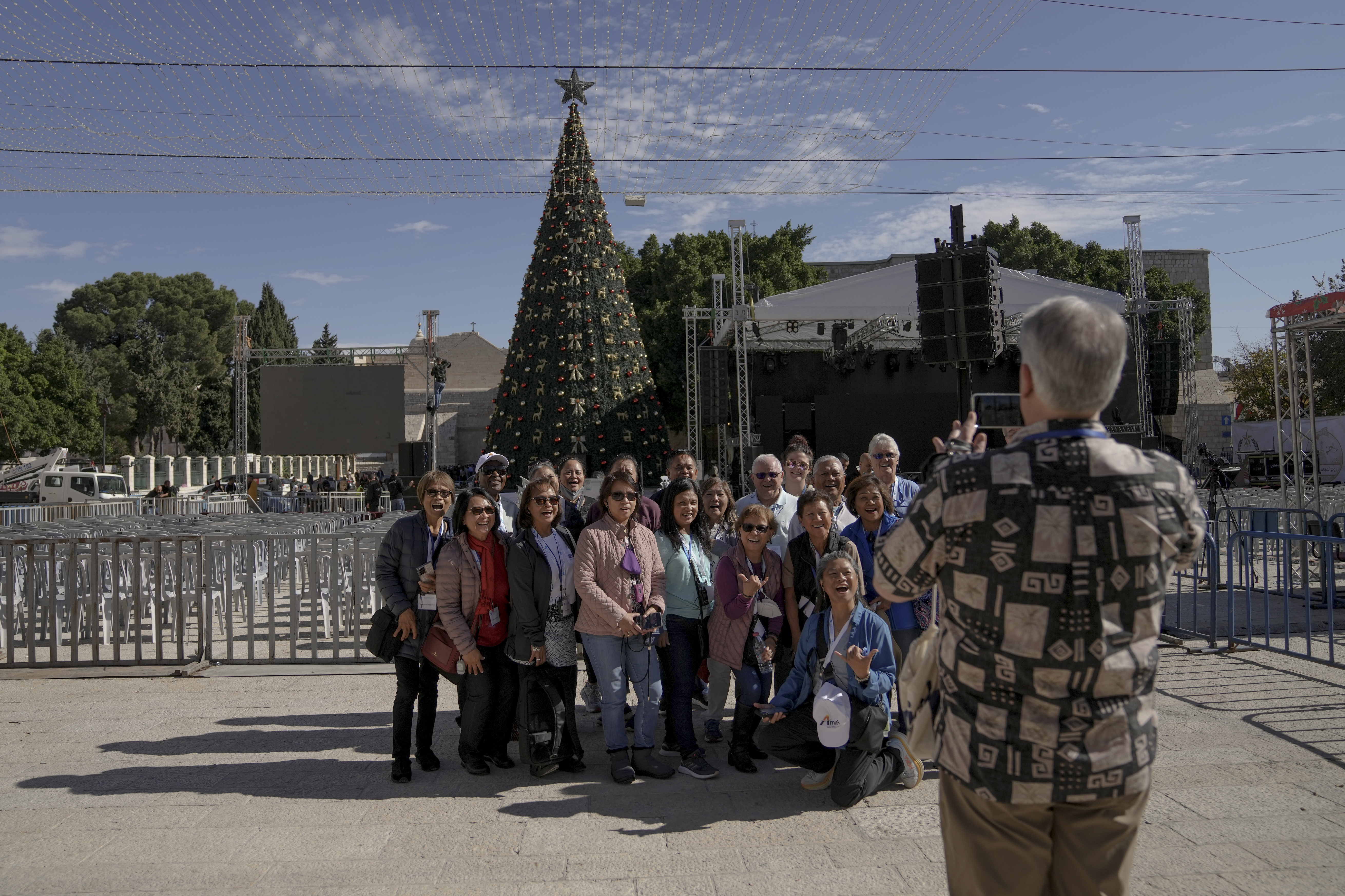 Tourists take pictures with the Christmas tree in Manger Square