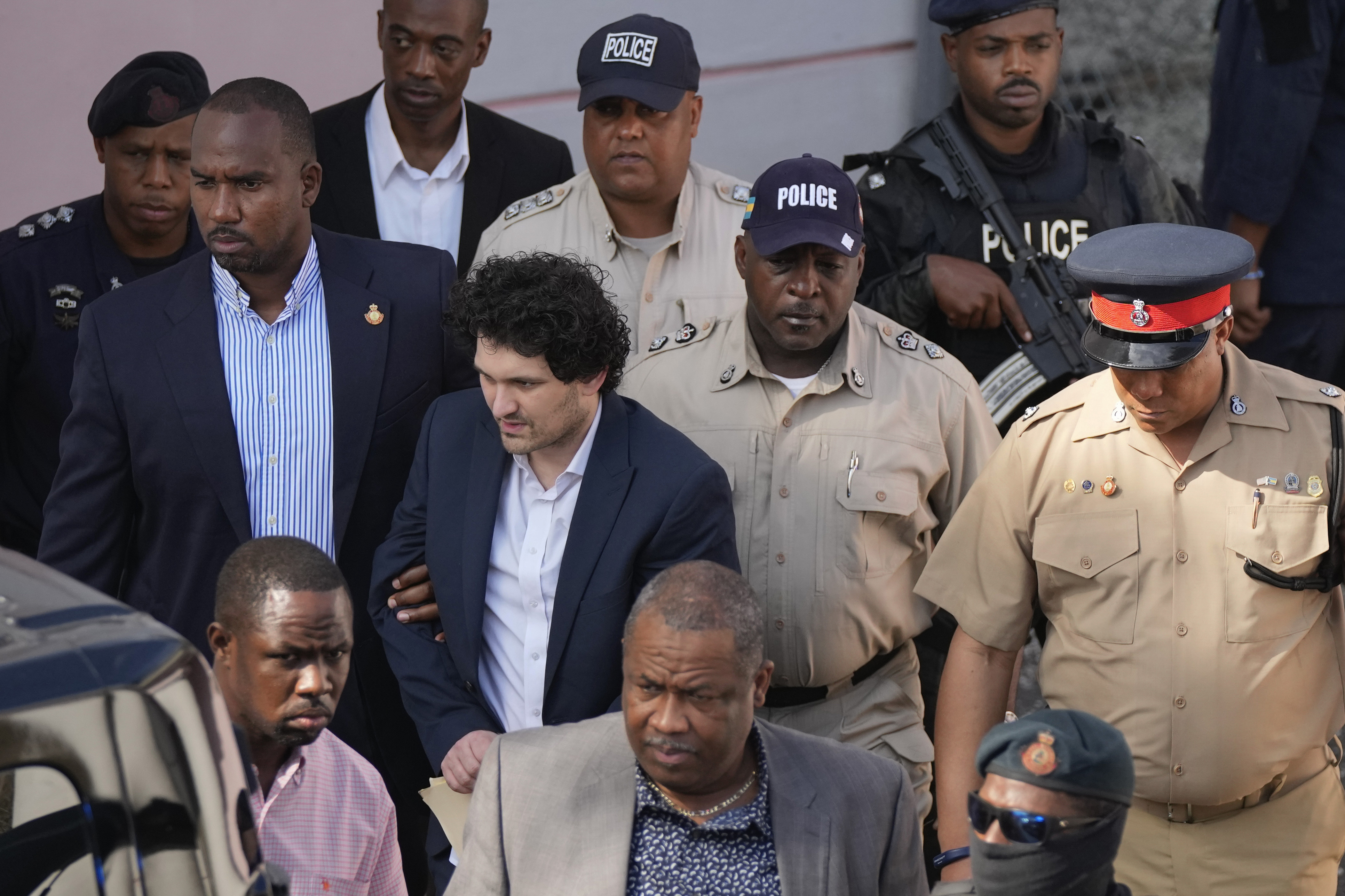 FTX founder Sam Bankman-Fried, center left, is escorted out of Magistrate Court into a Corrections van, following a hearing in Nassau, Bahamas