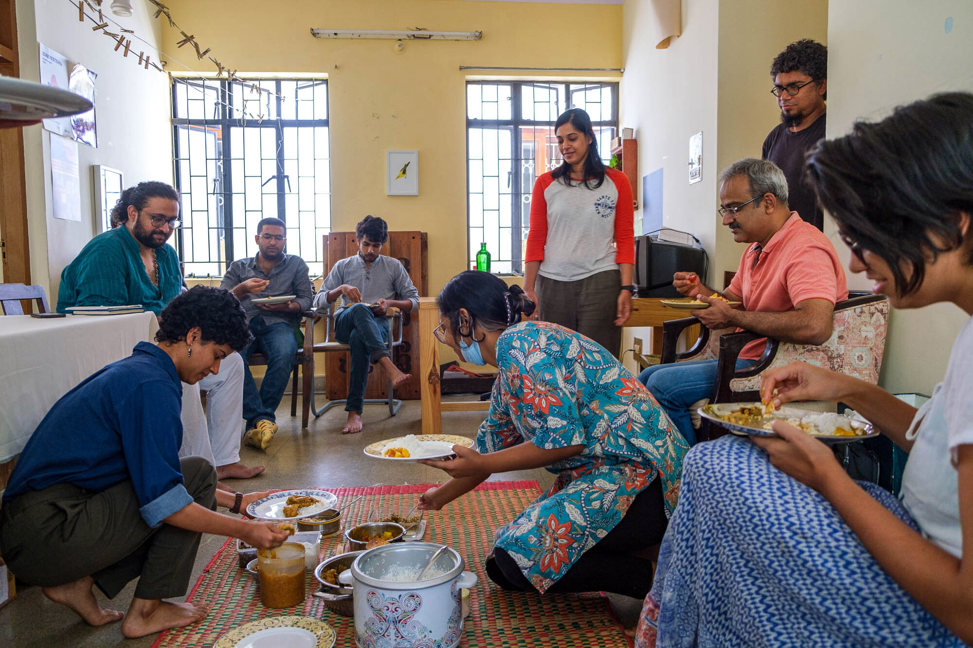 Sri Vamsi looks on as his guests serve themselves from food laid out on the mat