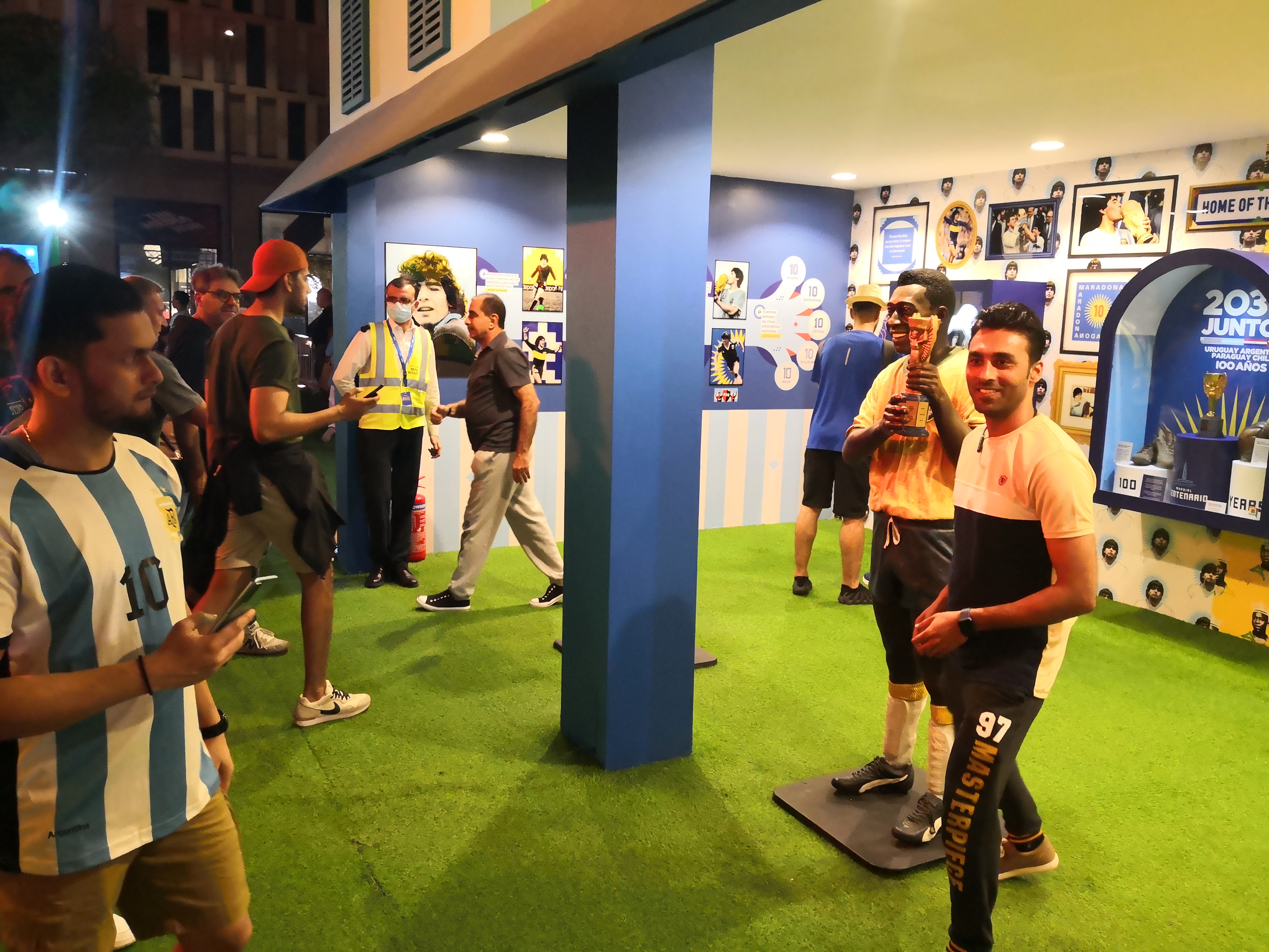 A fan taking a photo with a life-size statue of Pele holding aloft the World Cup trophy, at an exhibition on South American football in Doha on November 30, 2022. (Hafsa Adil/Al Jazeera)