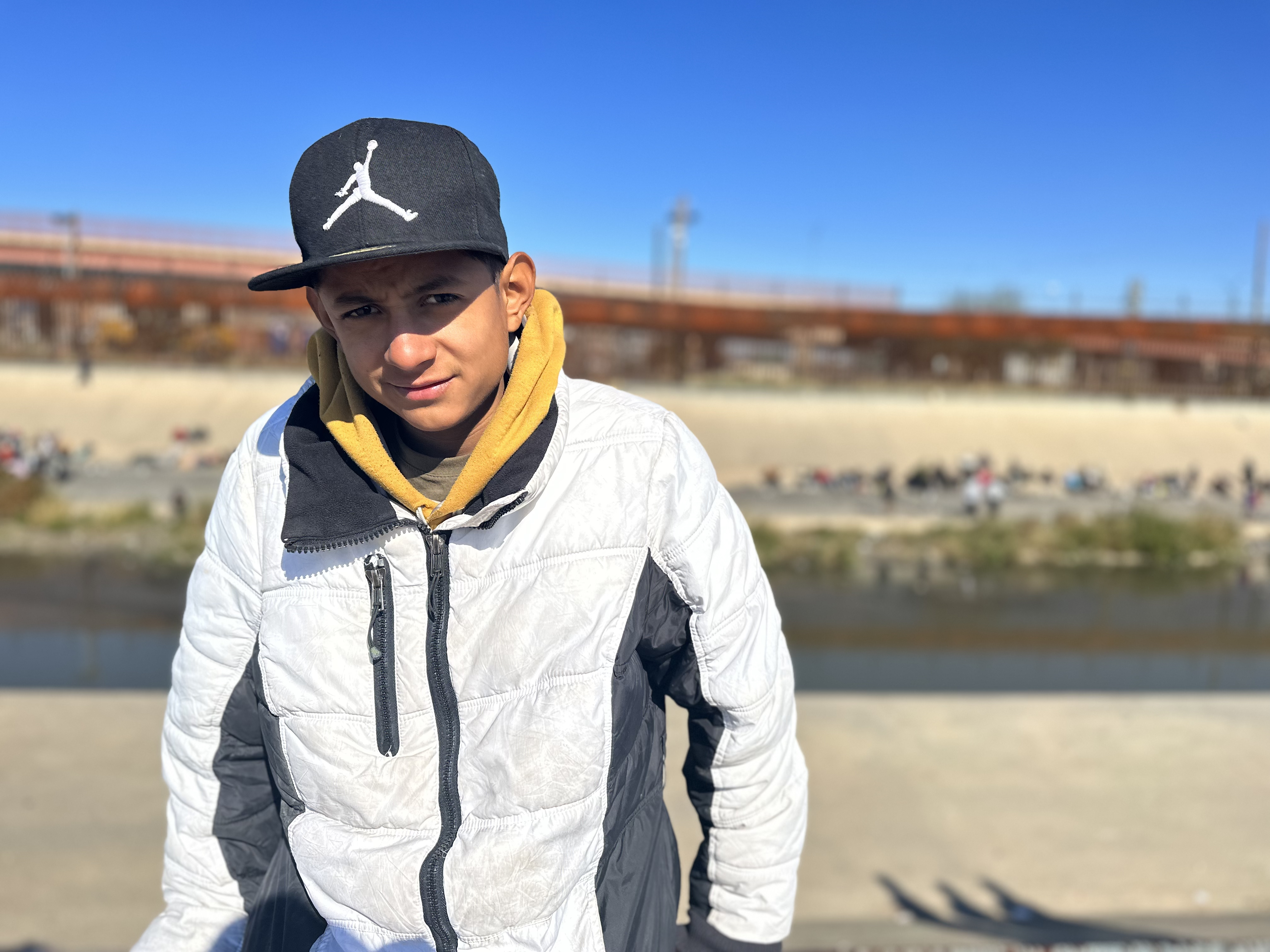 Juan Jose stands at the US-Mexico border, with the Rio Grande river in the background.