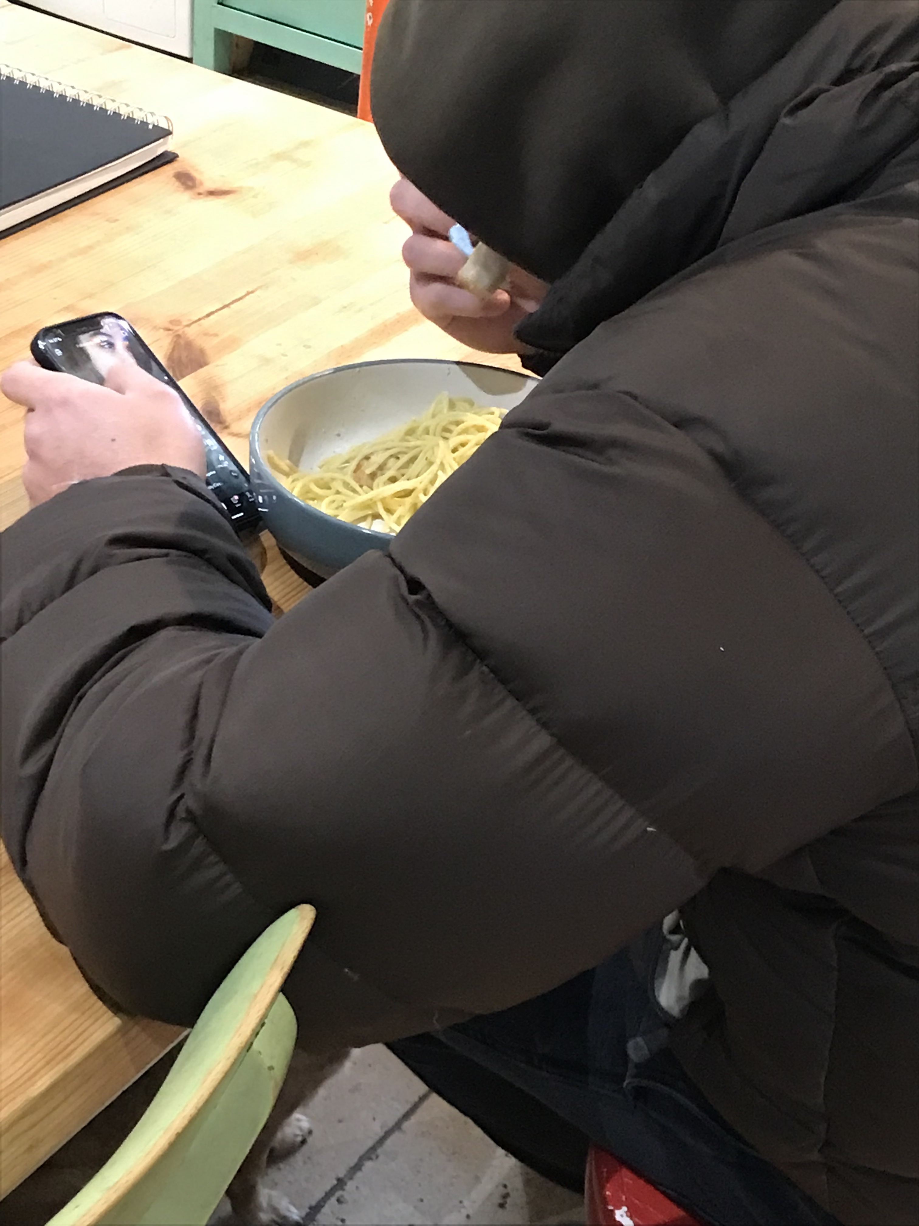 A person in a coat eating pasta