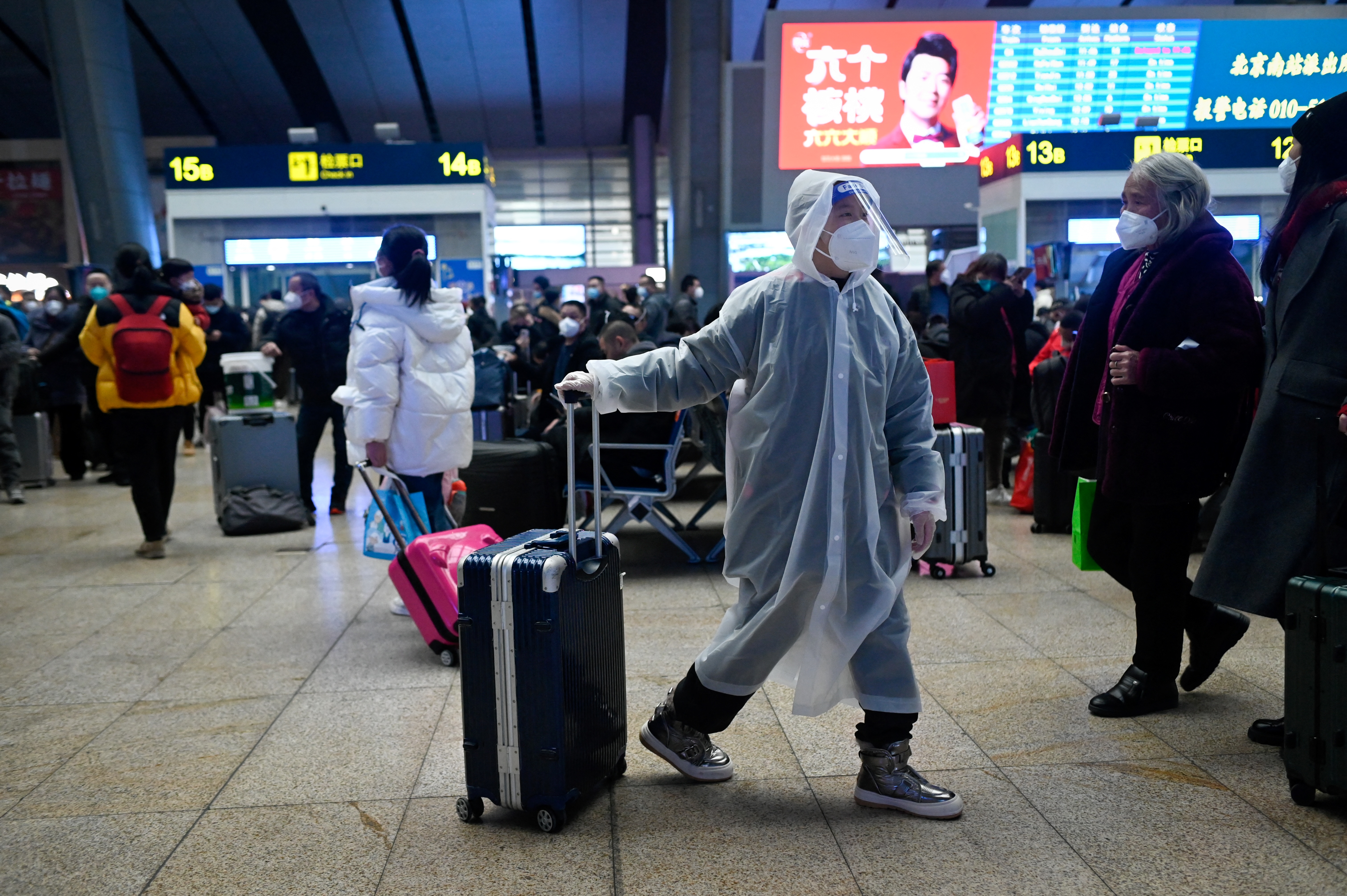 A child wearing a raincoat pulls his luggage at a railyway station in Beijing on January 12, 2023, as the annual migration begins with people heading back to their hometowns for Lunar New Year celebrations. (Photo by WANG ZHAO / AFP)