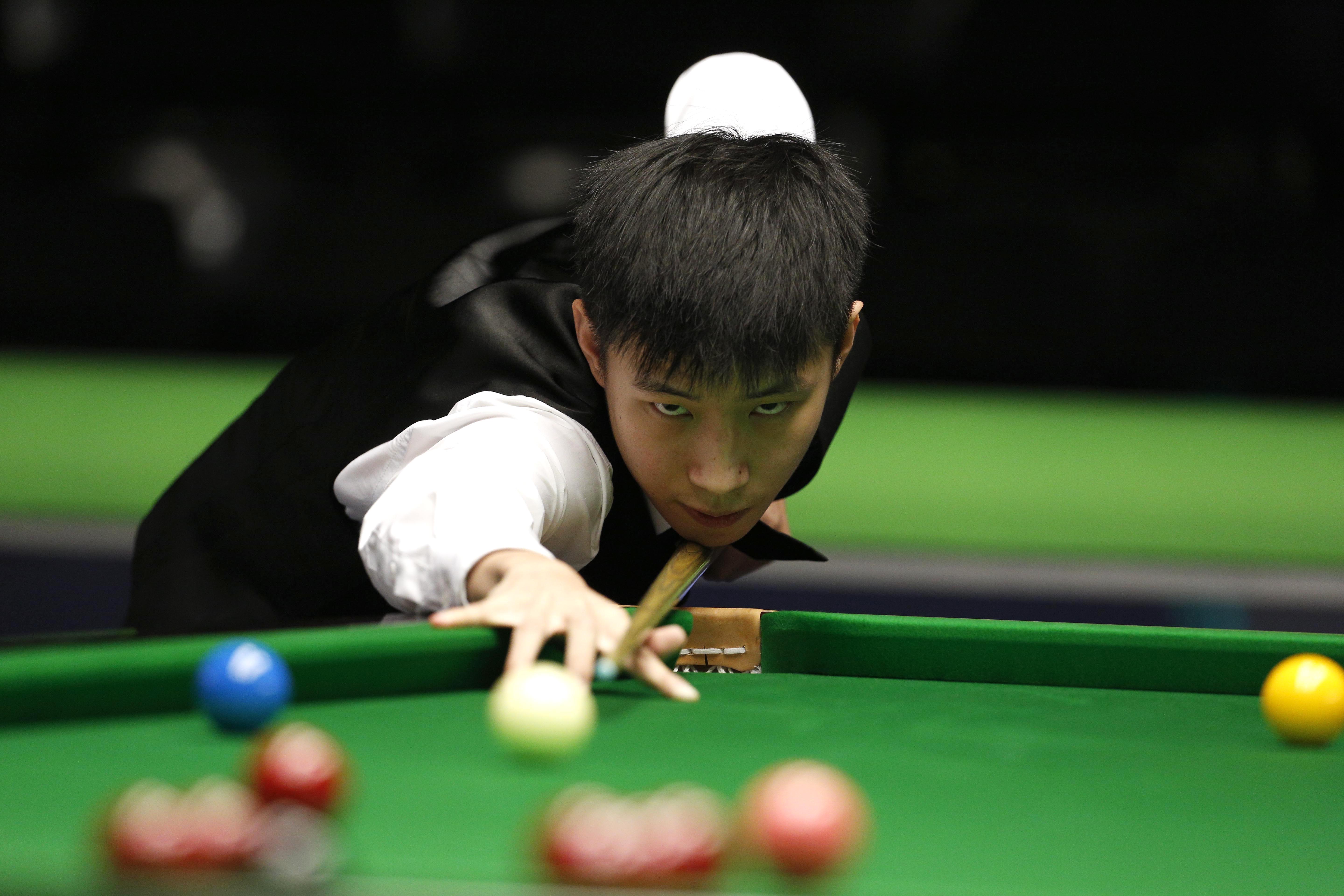 Chinese snooker player Zhao Xintong prepares to take a shot at the table