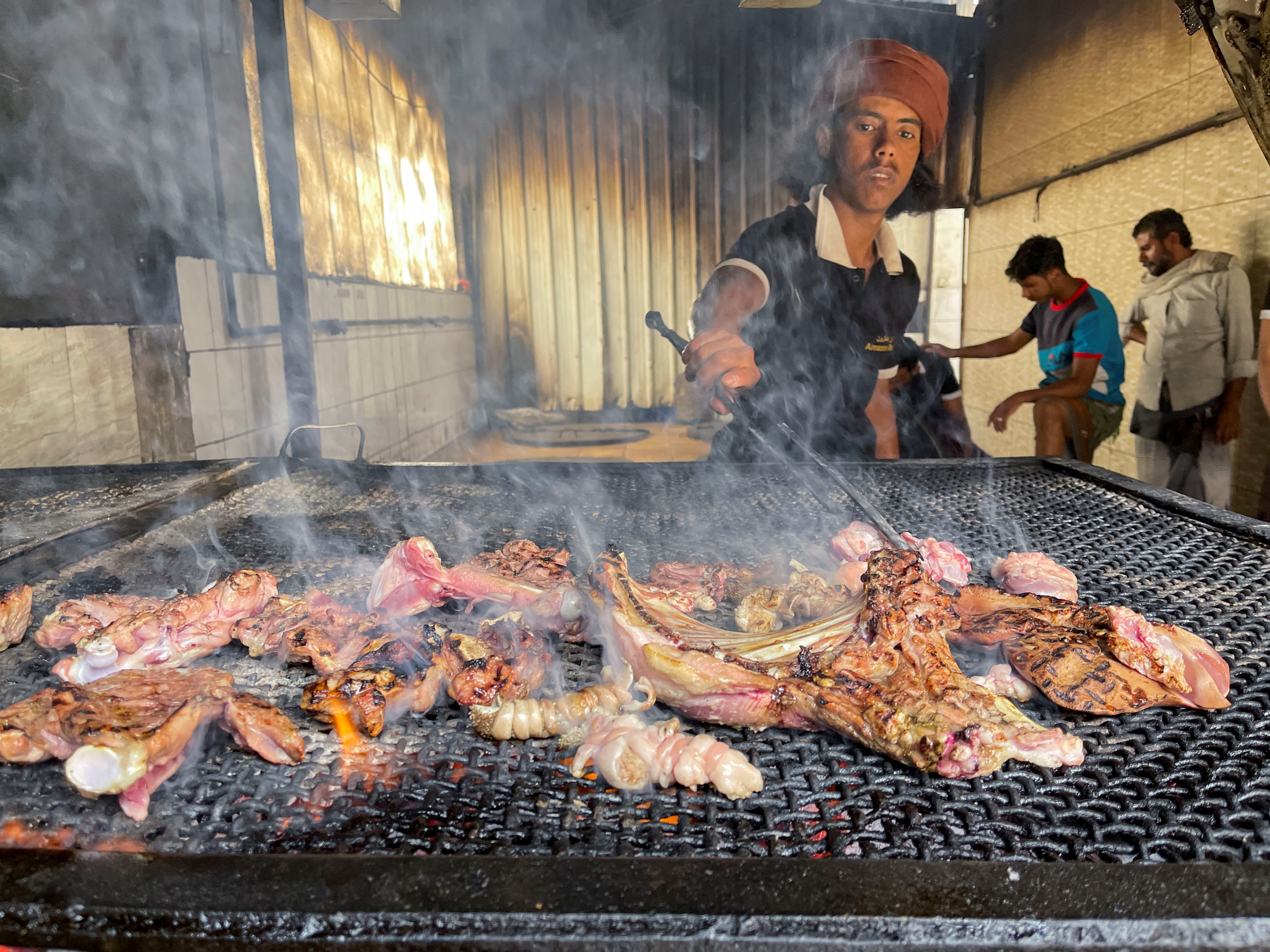 A cook grills meat at a restaurant in Sanaa, Yemen