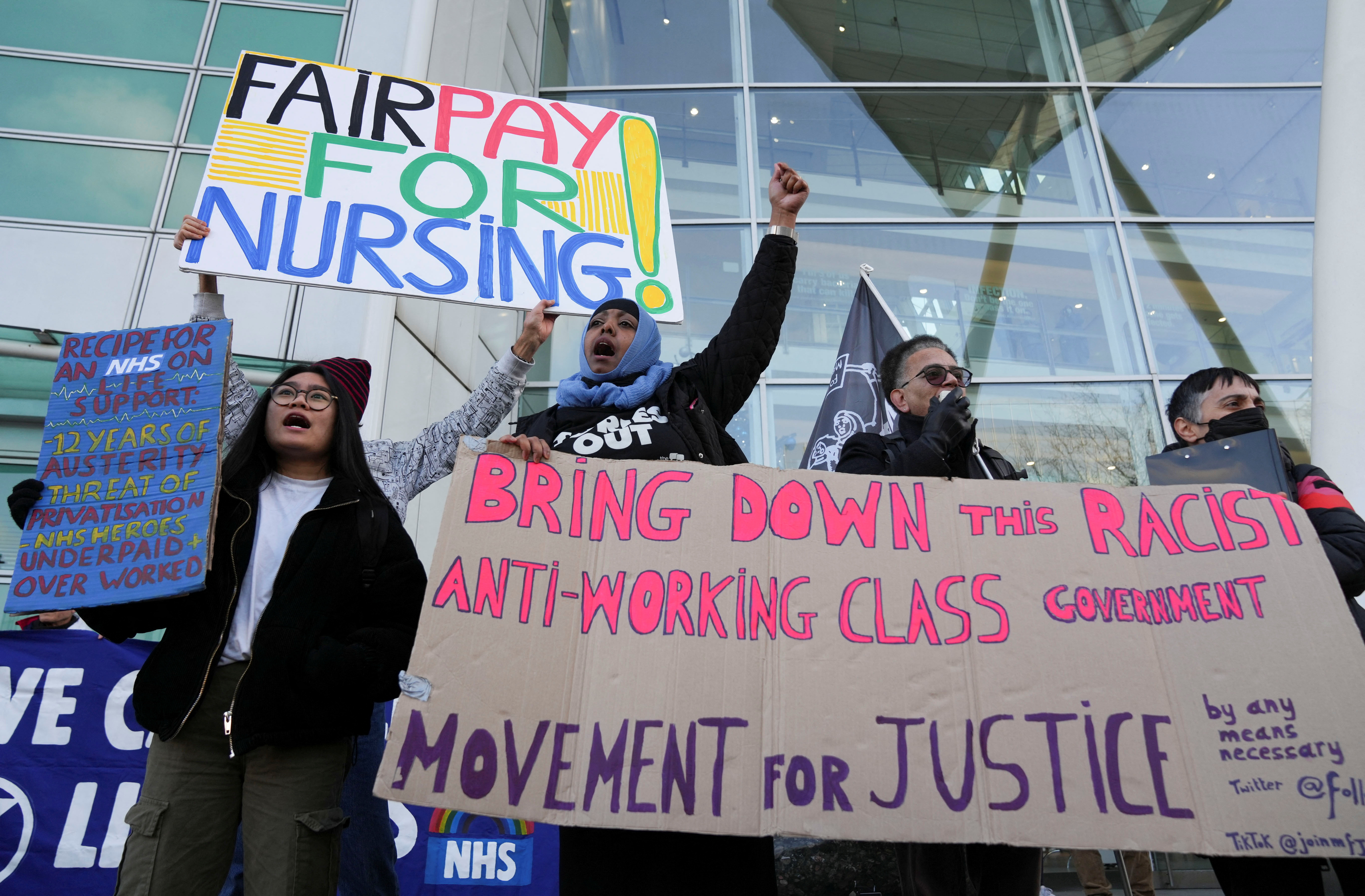 People hold signs outside University College Hospital as NHS nurses march during a strike, amid a dispute with the government over pay, in London