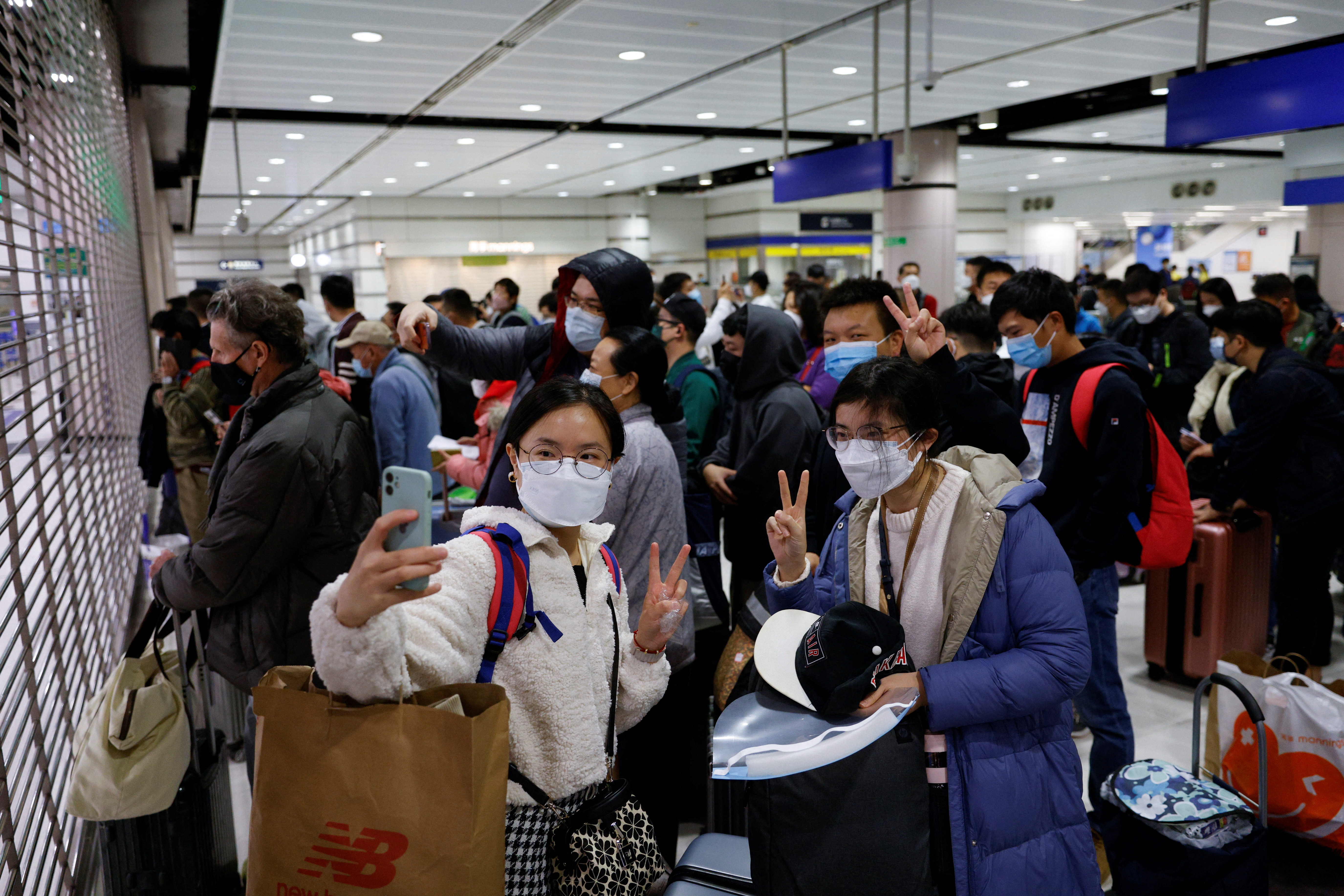 Travellers pose for photos at the gate of Hong Kong's Lok Ma Chau border checkpoint before China reopens the border.