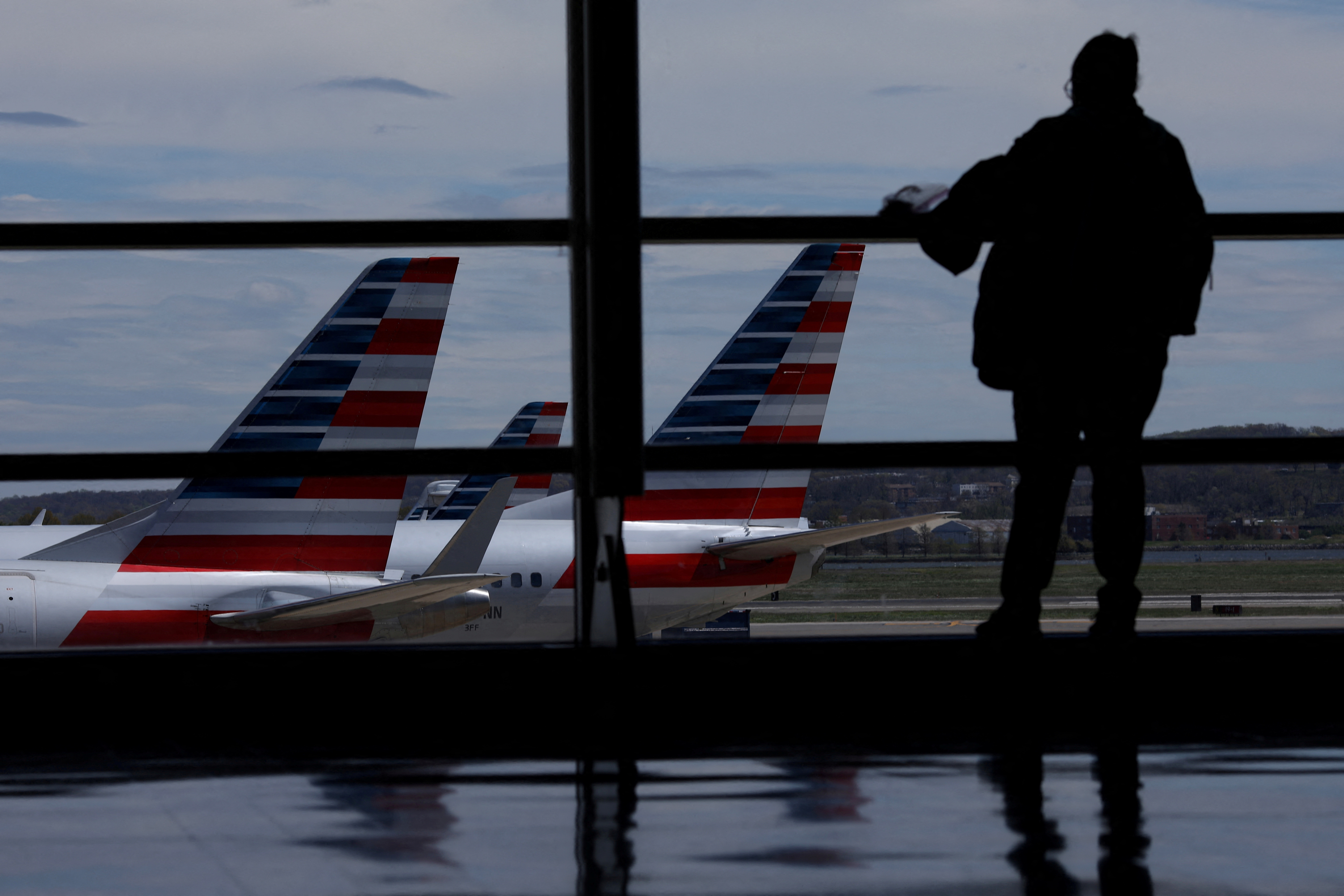 man looks at planes through window