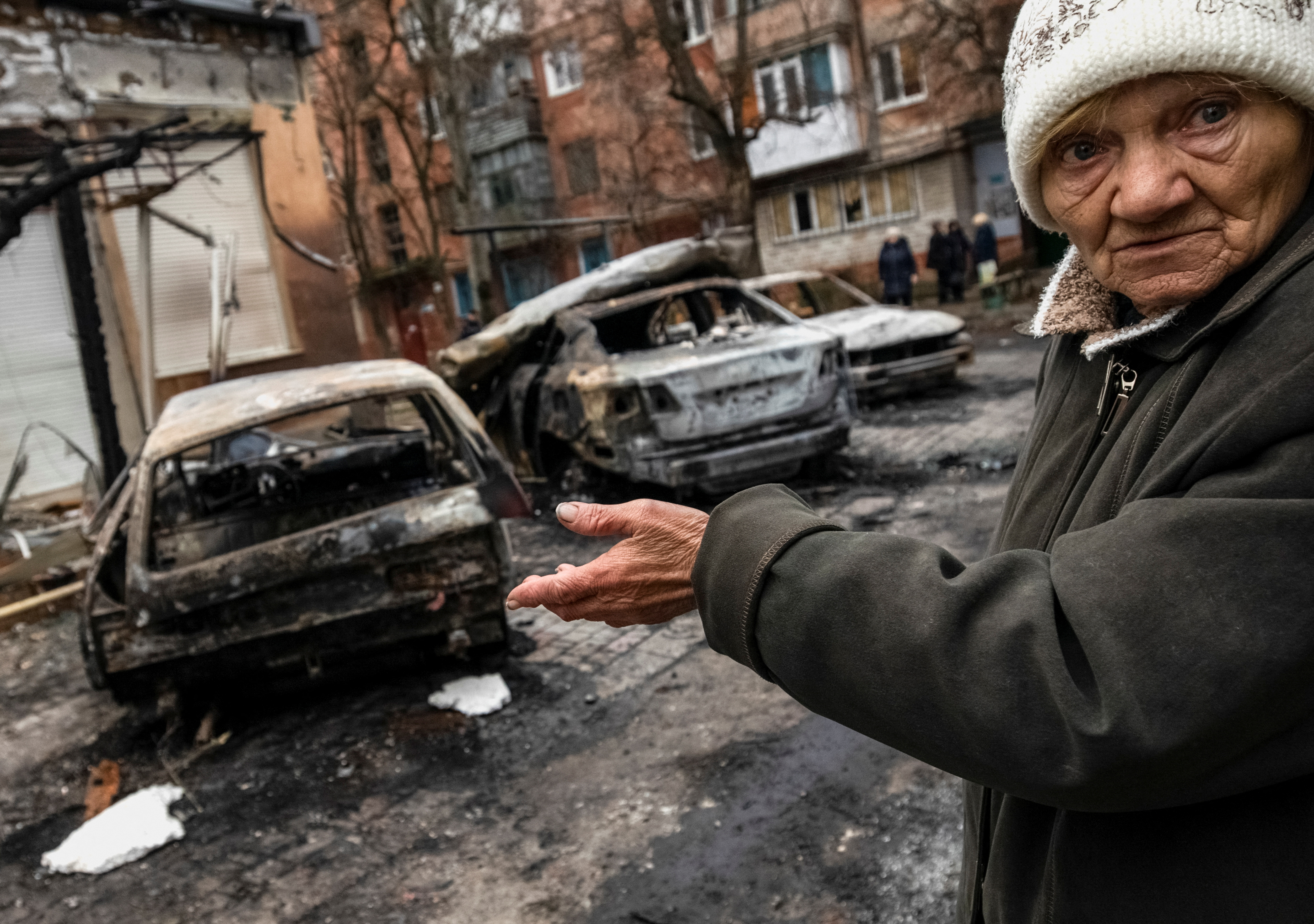 A local resident gestures near burned cars destroyed by a Russian military strike in Kherson