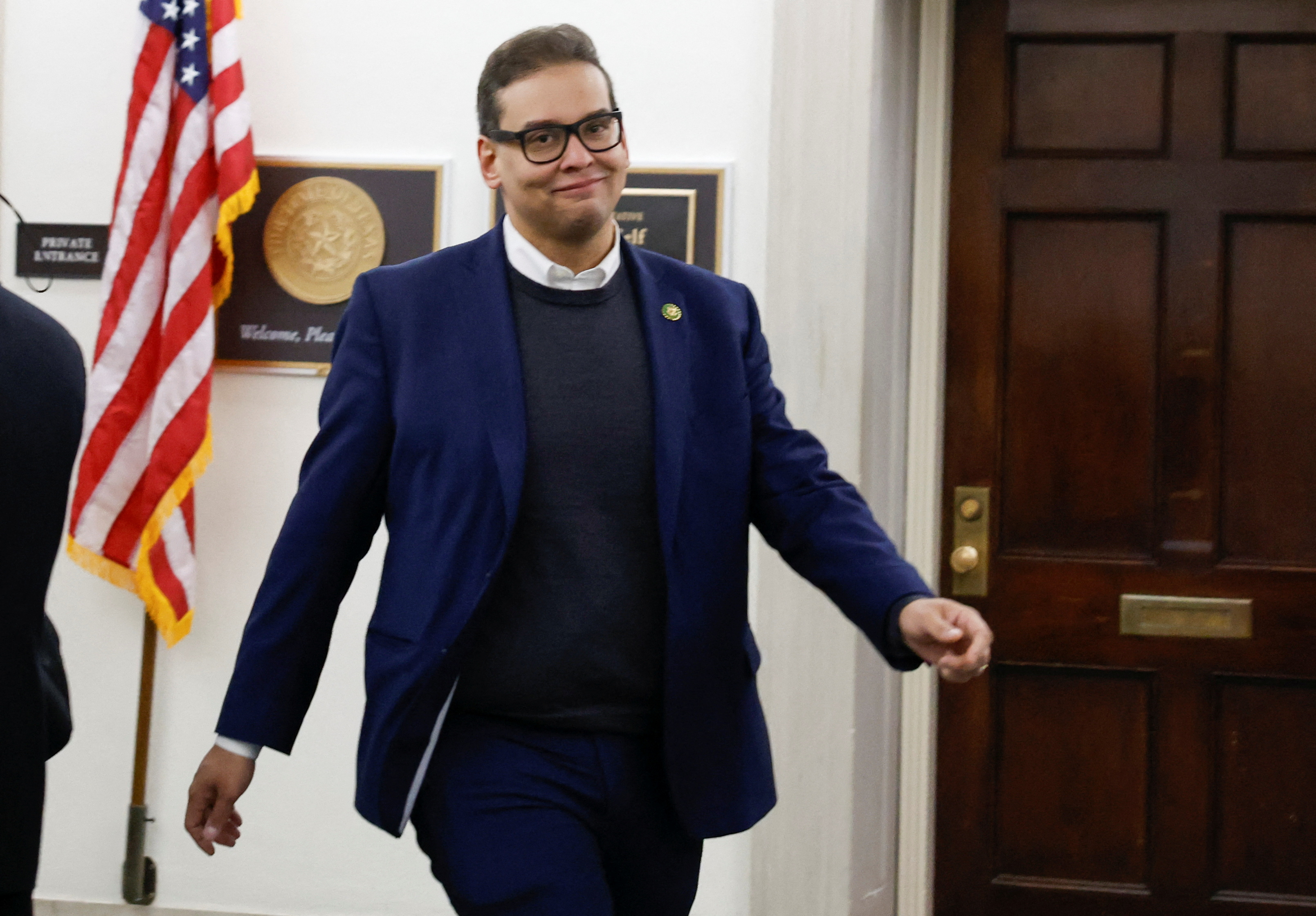 George Santos walks past a US flag while walking back to his office.