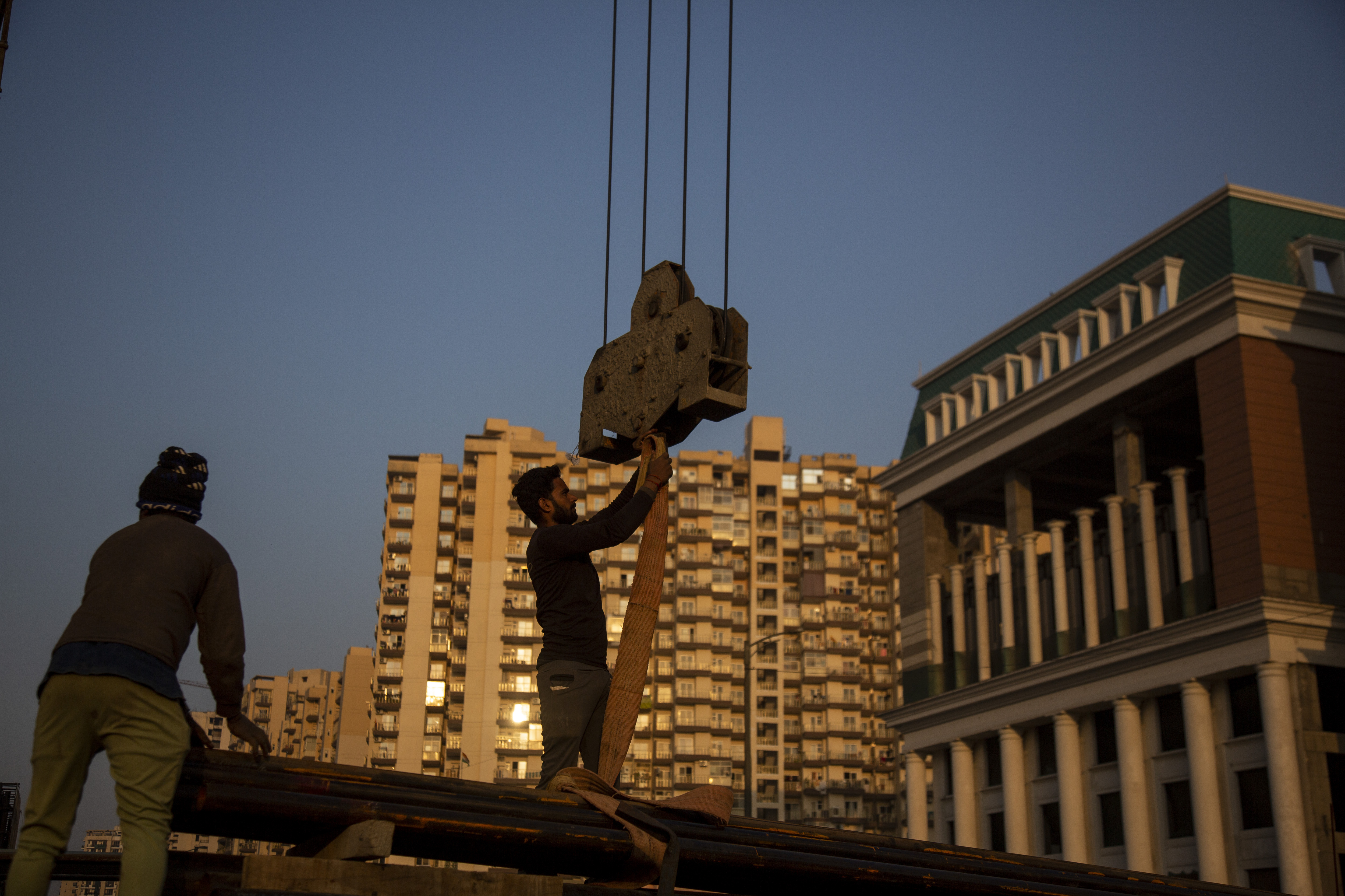 Workers handle building construction material in Greater Noida, India