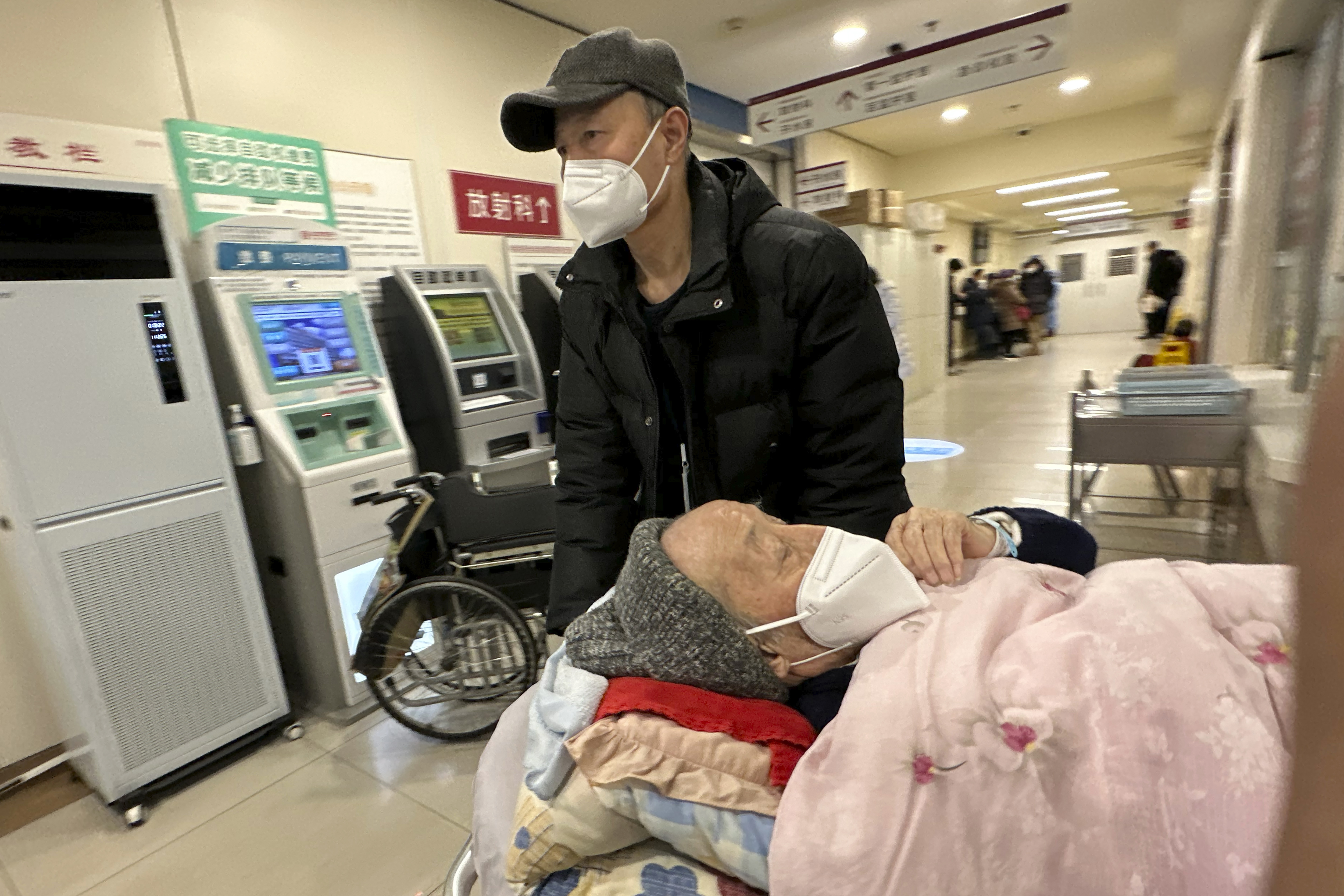 An elderly patient is pushed along a corridor of the emergency ward at a hospital in Beijing, Saturday, Dec. 31, 2022. China is on a bumpy road back to normal life as schools, shopping malls and restaurants fill up again with the easing of COVID-19 restriction. The abrupt end to testing and other measures came as hospitals were swamped with feverish, wheezing COVID-19 patients