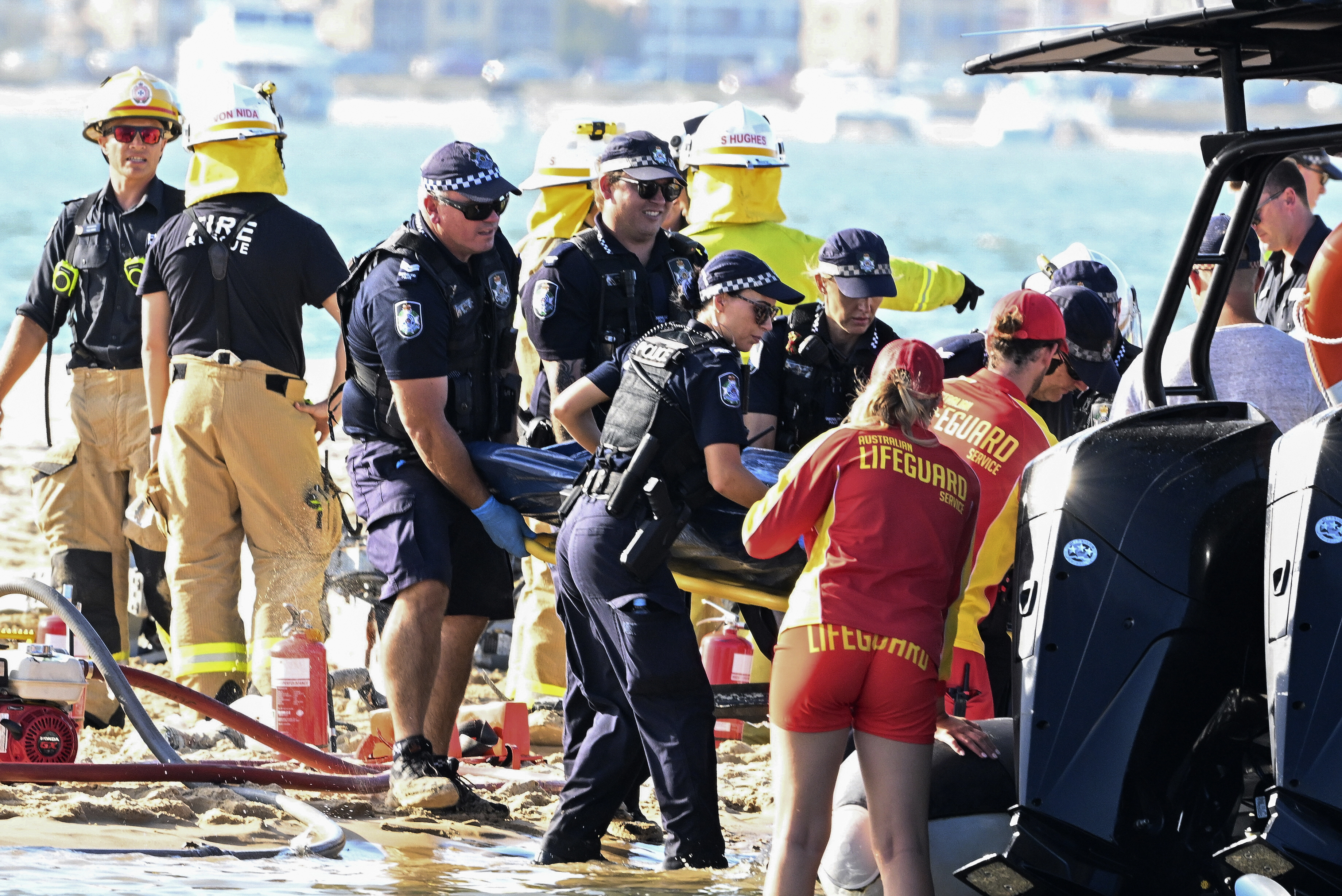 Emergency workers remove a body from a helicopter collision scene near Seaworld, on the Gold Coast, Australia, Monday, Jan. 2, 2023
