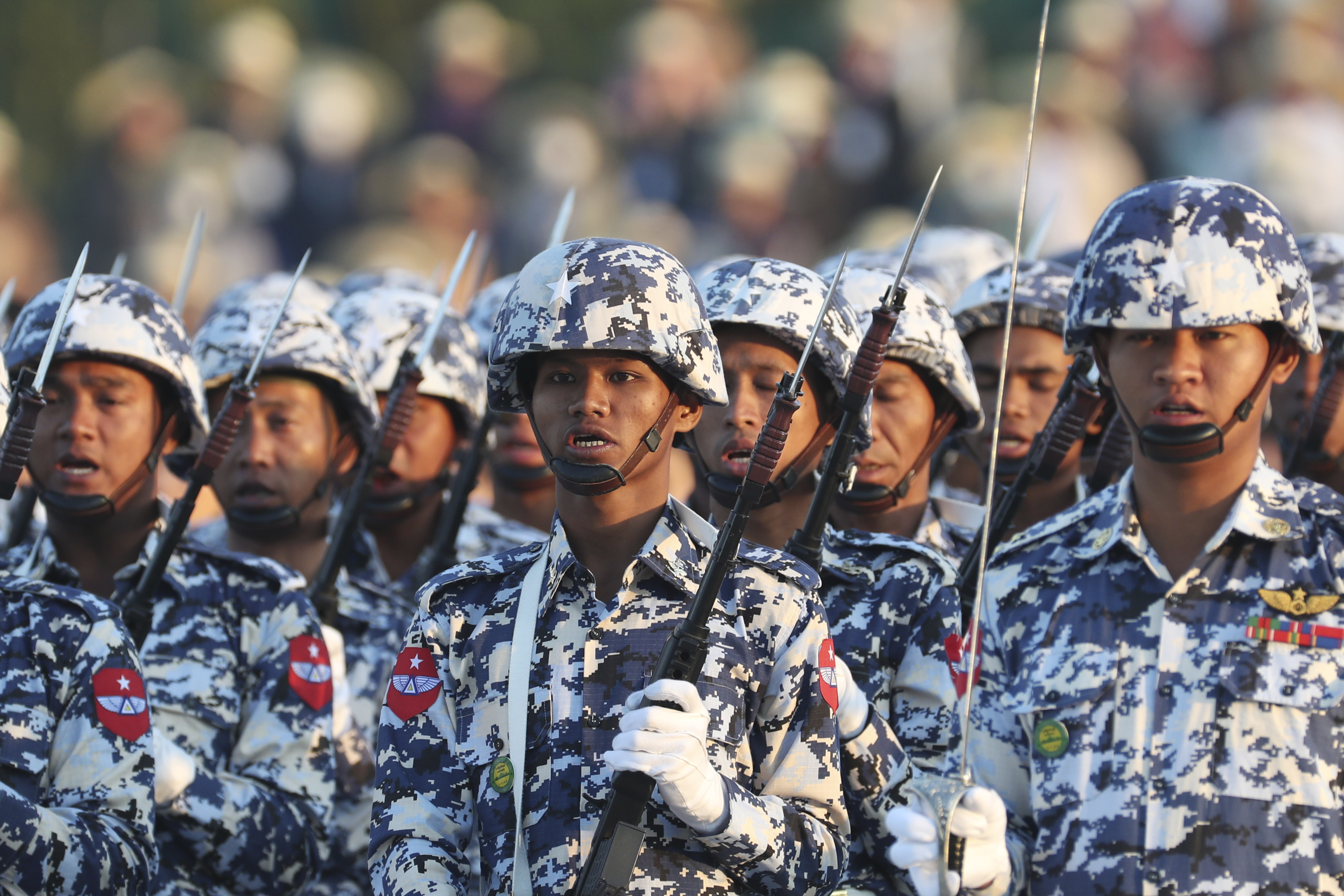 Myanmar soldiers in uniform and carrying weapons march at a ceremony marking Myanmar's 75th day of independence