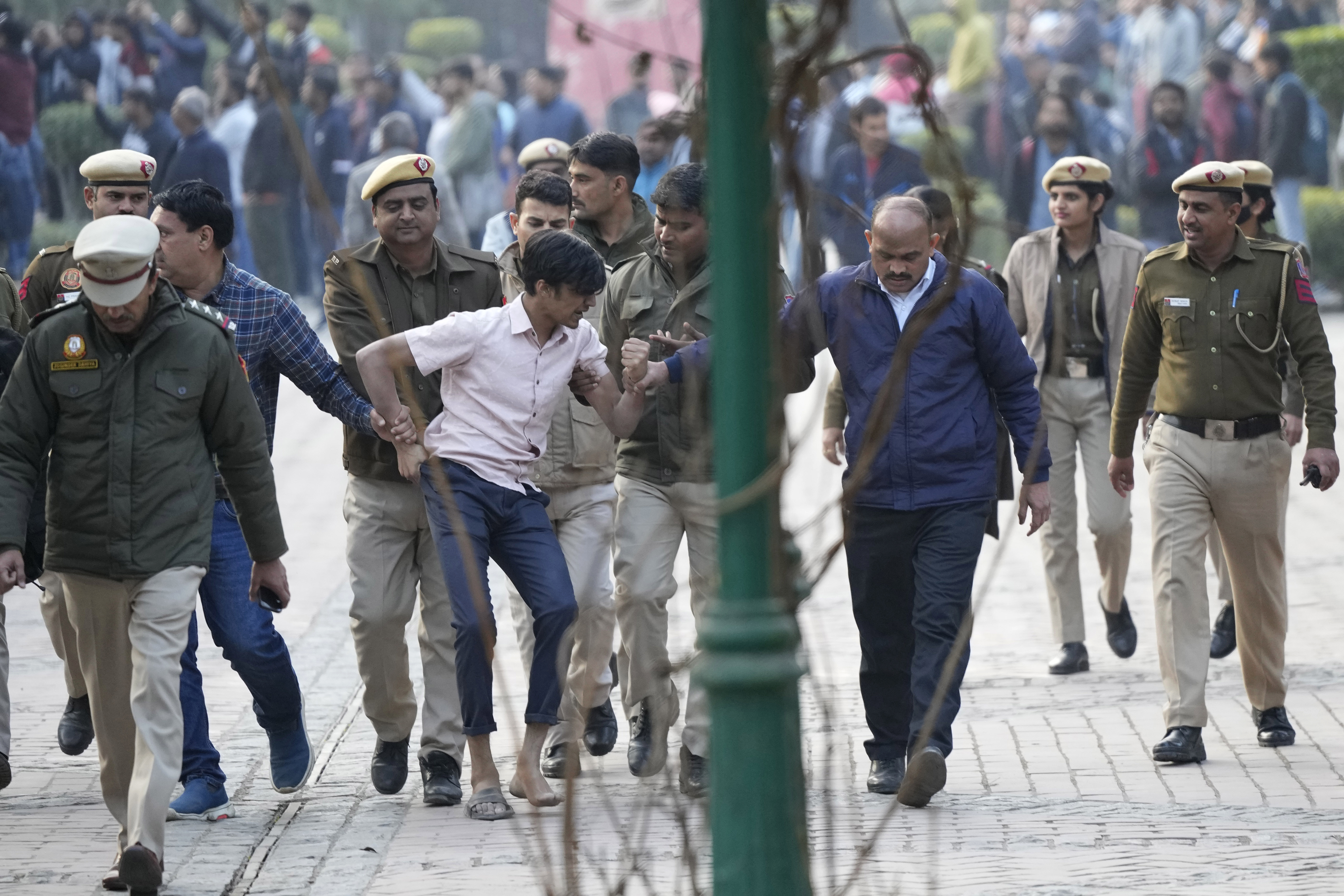 Policemen and security guards of Delhi University escort a protesting student out