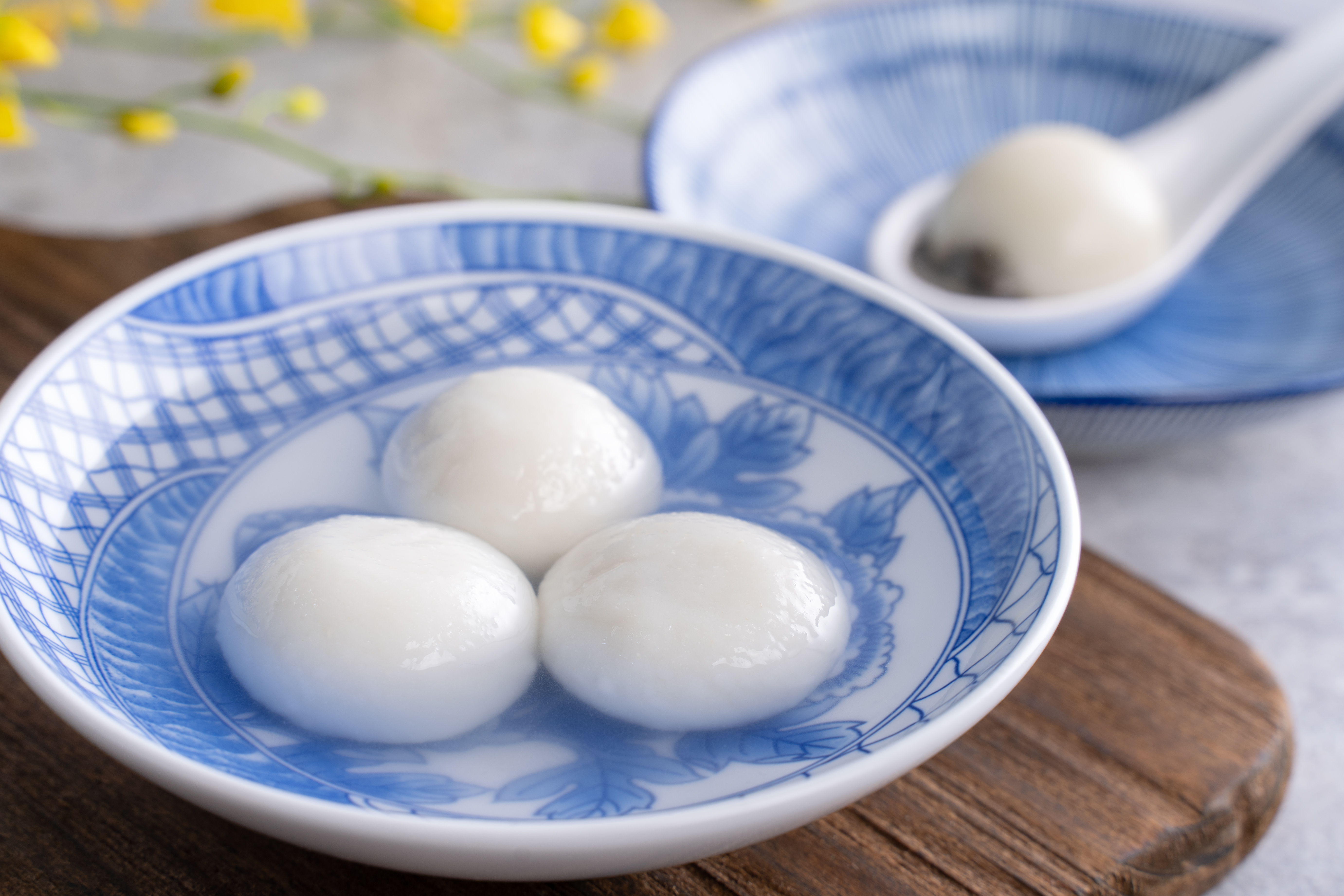 blue and white bowl with rice balls in it in a ginger syrup