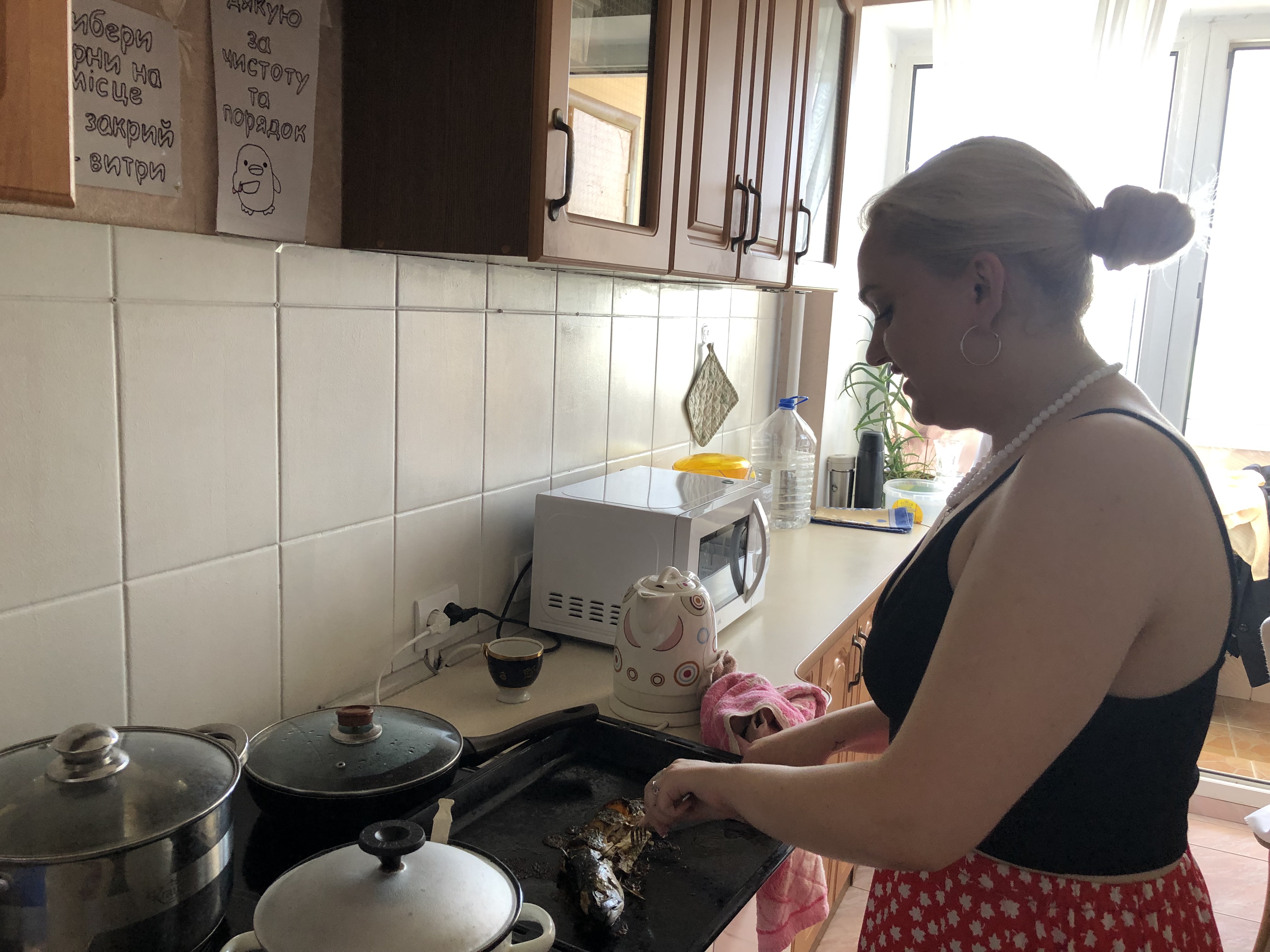 A photo of Mira cutting a fish in the kitchen.