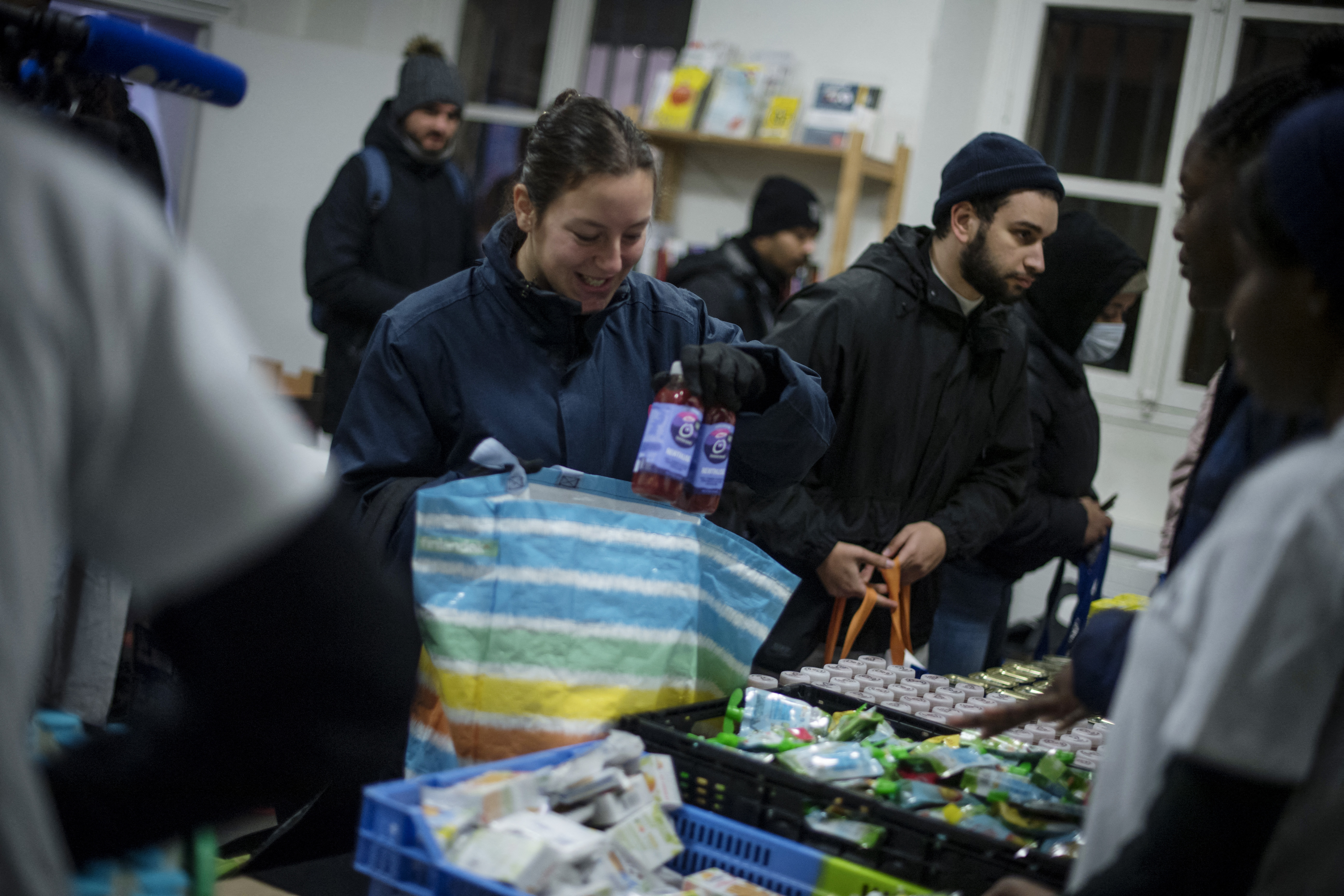 French sports student Lena Christien takes food products during a student food aid distribution in Paris, on December 15, 2022. - Since this year a significant number of young students have resorted to food distributions as a result of inflation and the sharp rise in the price of basic necessities. (Photo by JULIEN DE ROSA / AFP)