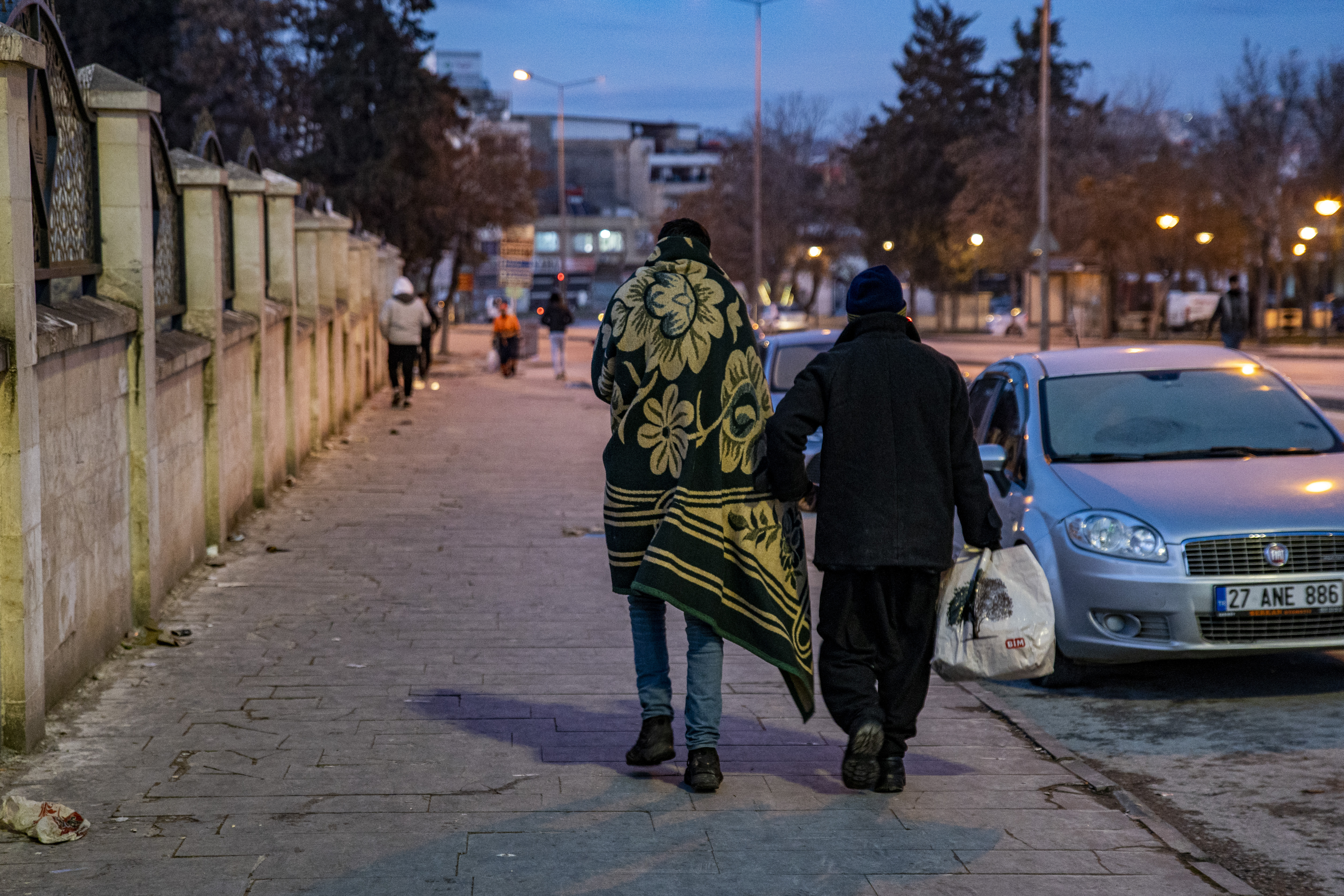 A Syrian father and son emotionally comfort each other with words of encouragement as they walk towards the closest public shelter put in place by the municipality, to overcome the population’s emergency needs