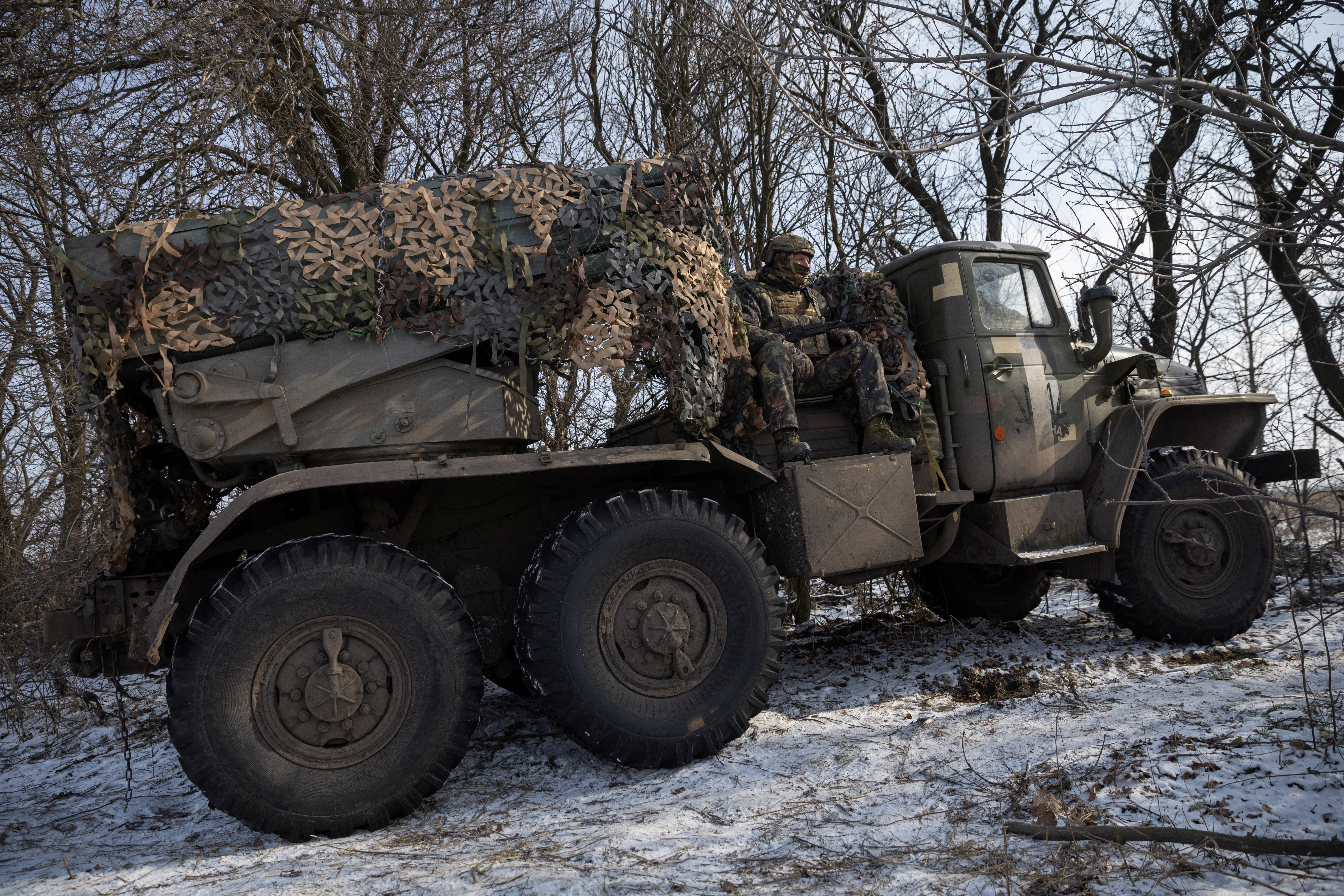Ukrainian servicemen ride in a BM-21 Grad multiple launch rocket system as they prepare to fire it towards Russian positions on a frontline near the town of Marinka