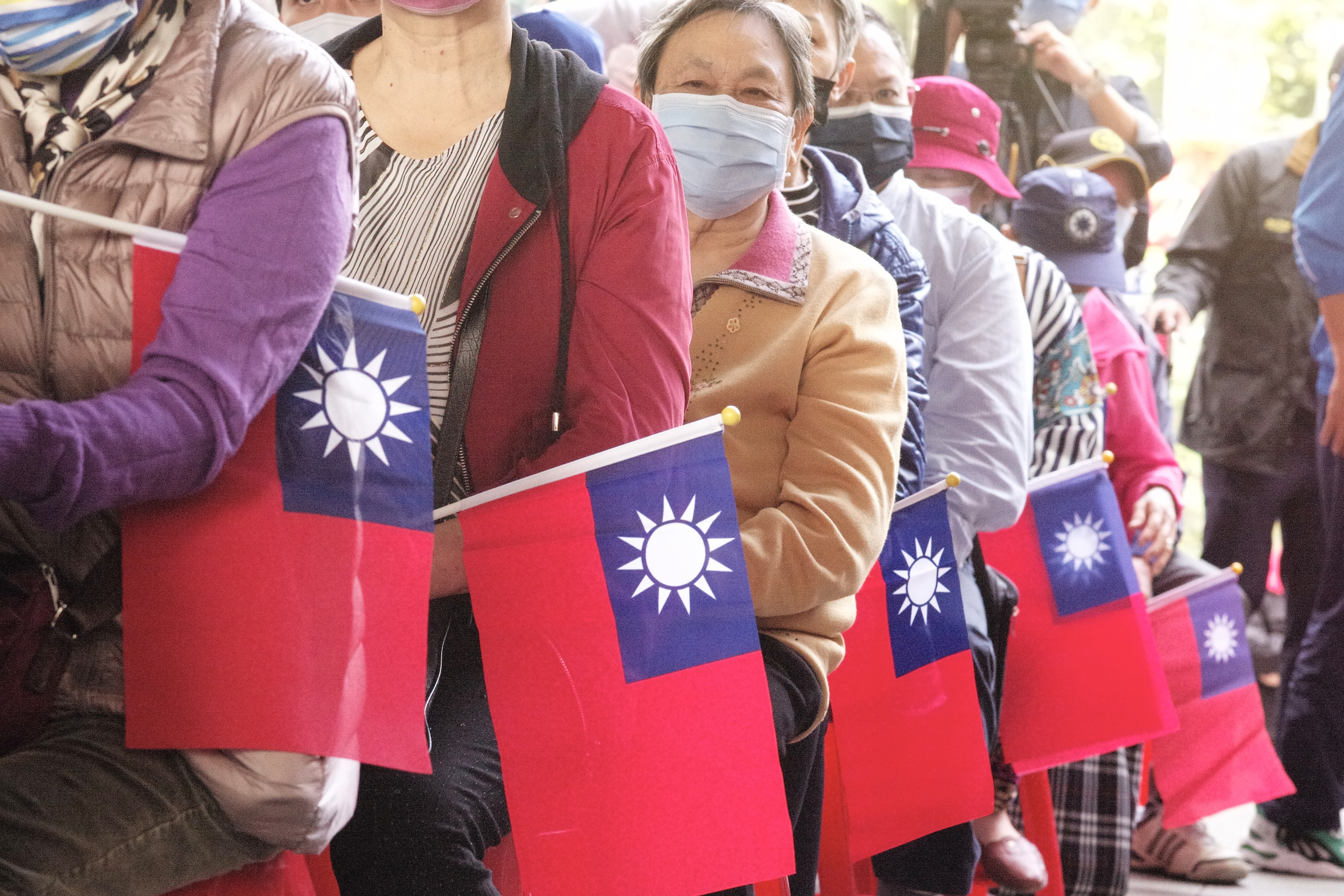 KMT supporters standing in a line holding small Taiwan flags.