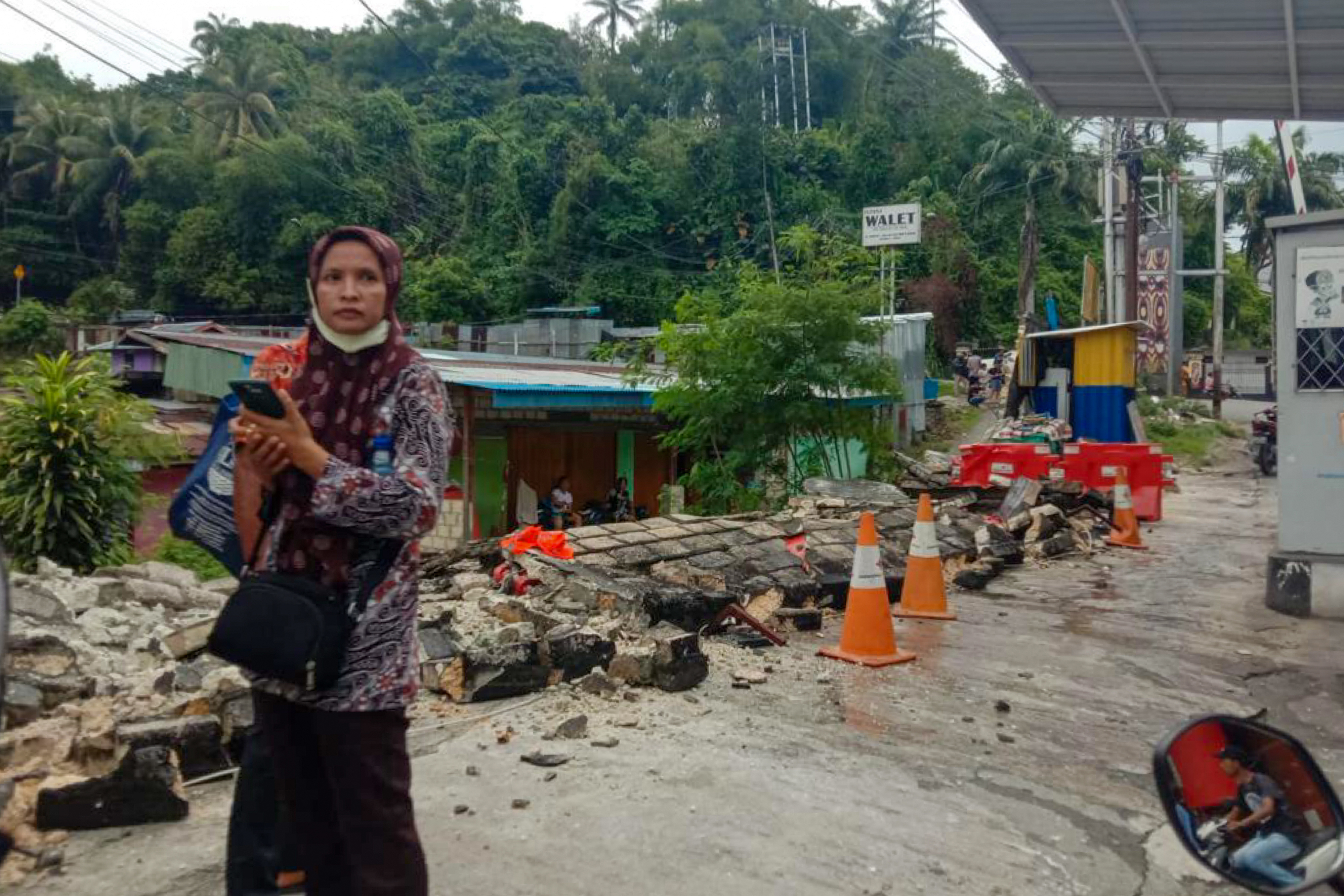 A woman stands next to a collapsed wall after a 5.4-magnitude earthquake in Jayapura, Indonesia's eastern province of Papua on February 9, 2023. (Photo by FAISAL NARWAWAN / AFP)