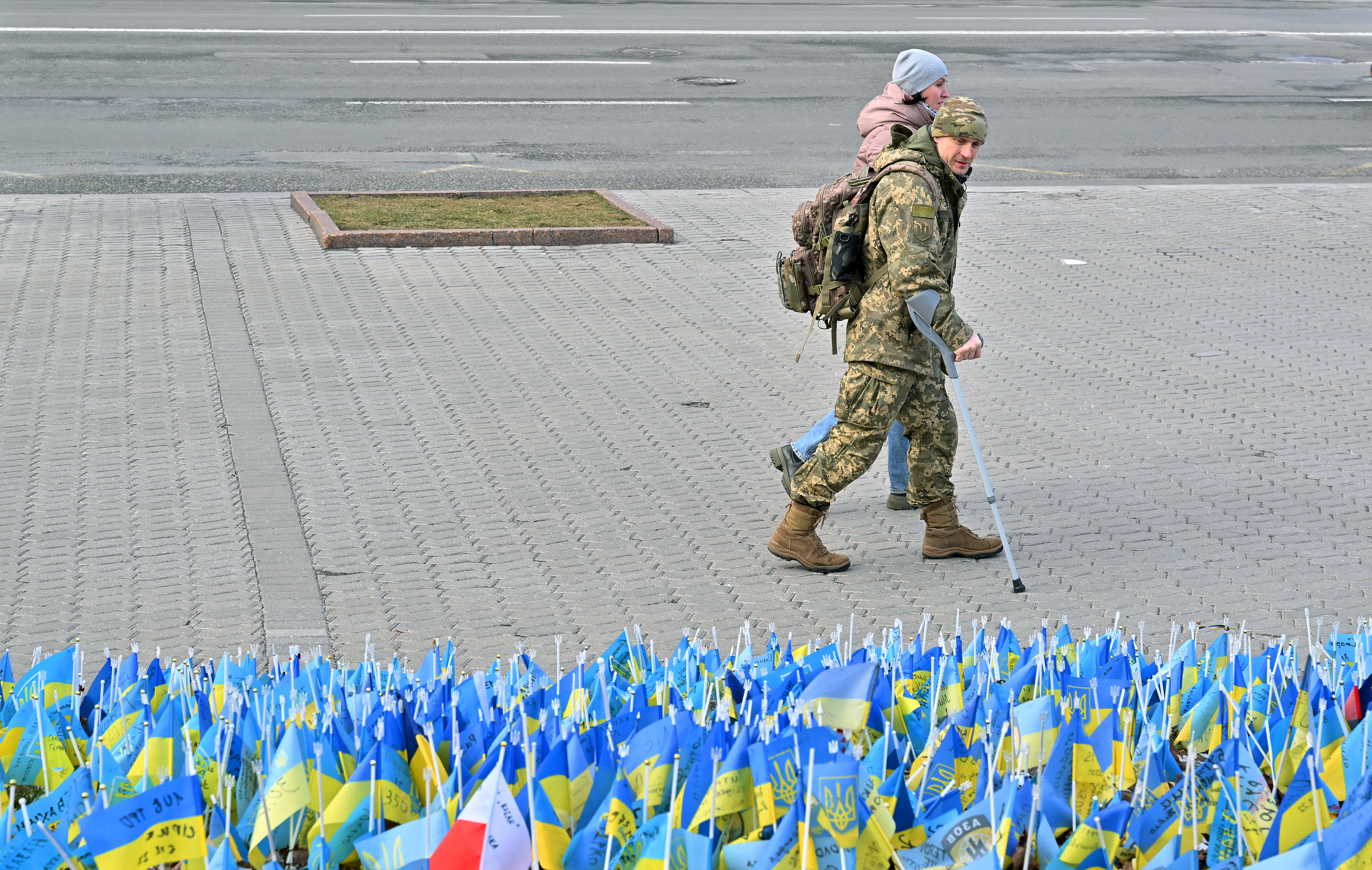 A wounded Ukrainian serviceman and his girlfriend walk past national flags