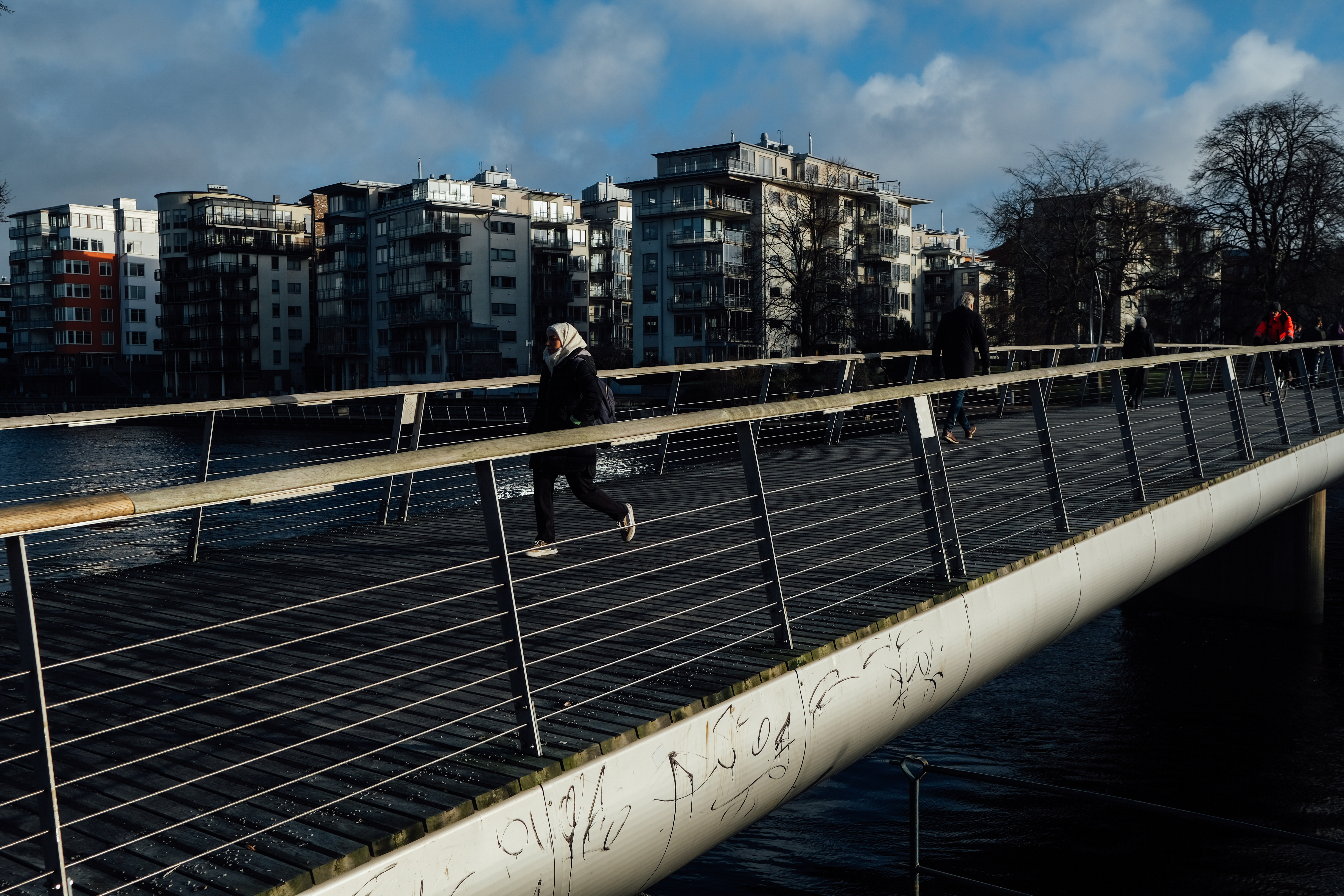 People walk along a bridge over a river