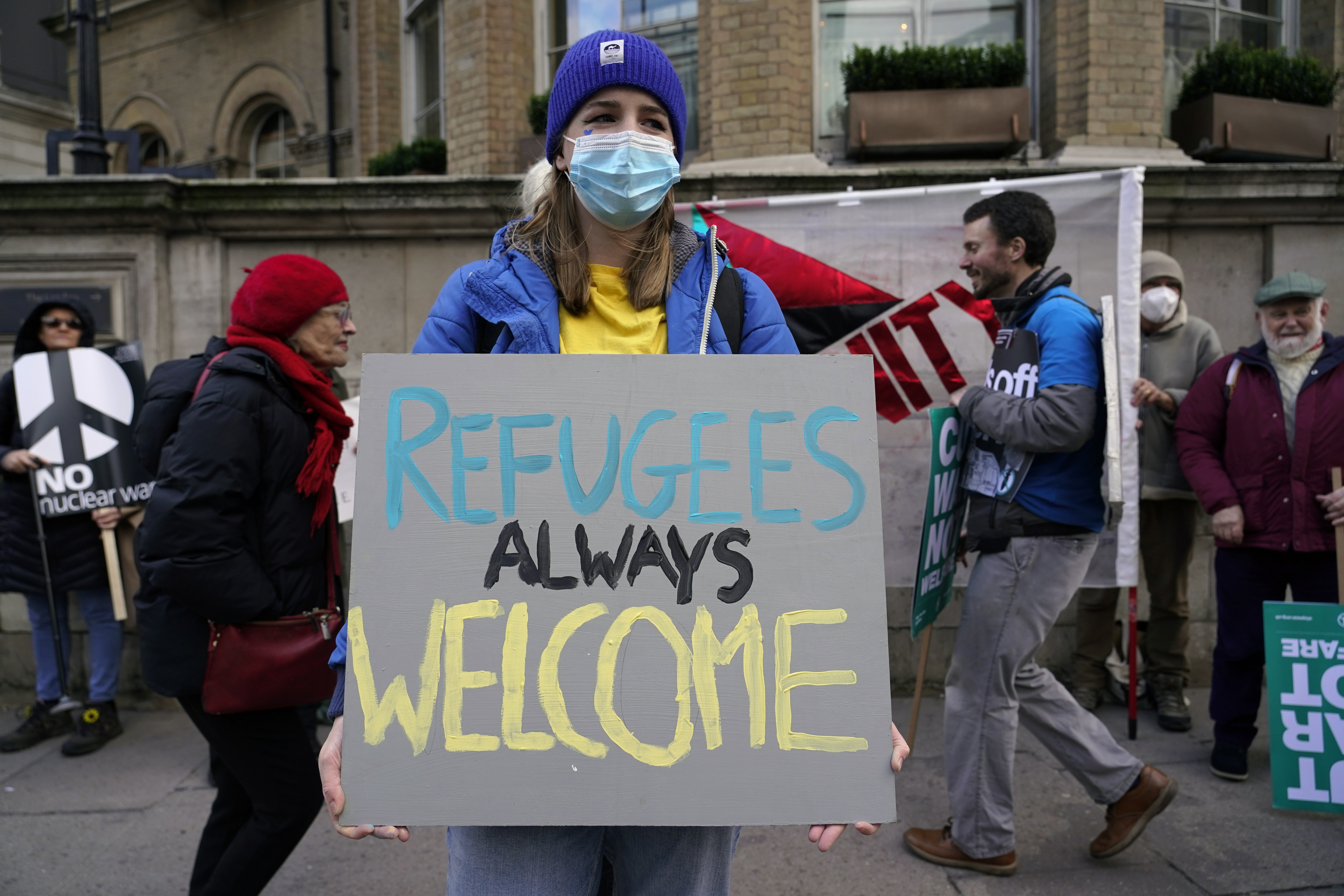 A demonstrator holds a placard saying 'Refugees always welcome' during an anti-war march, in London