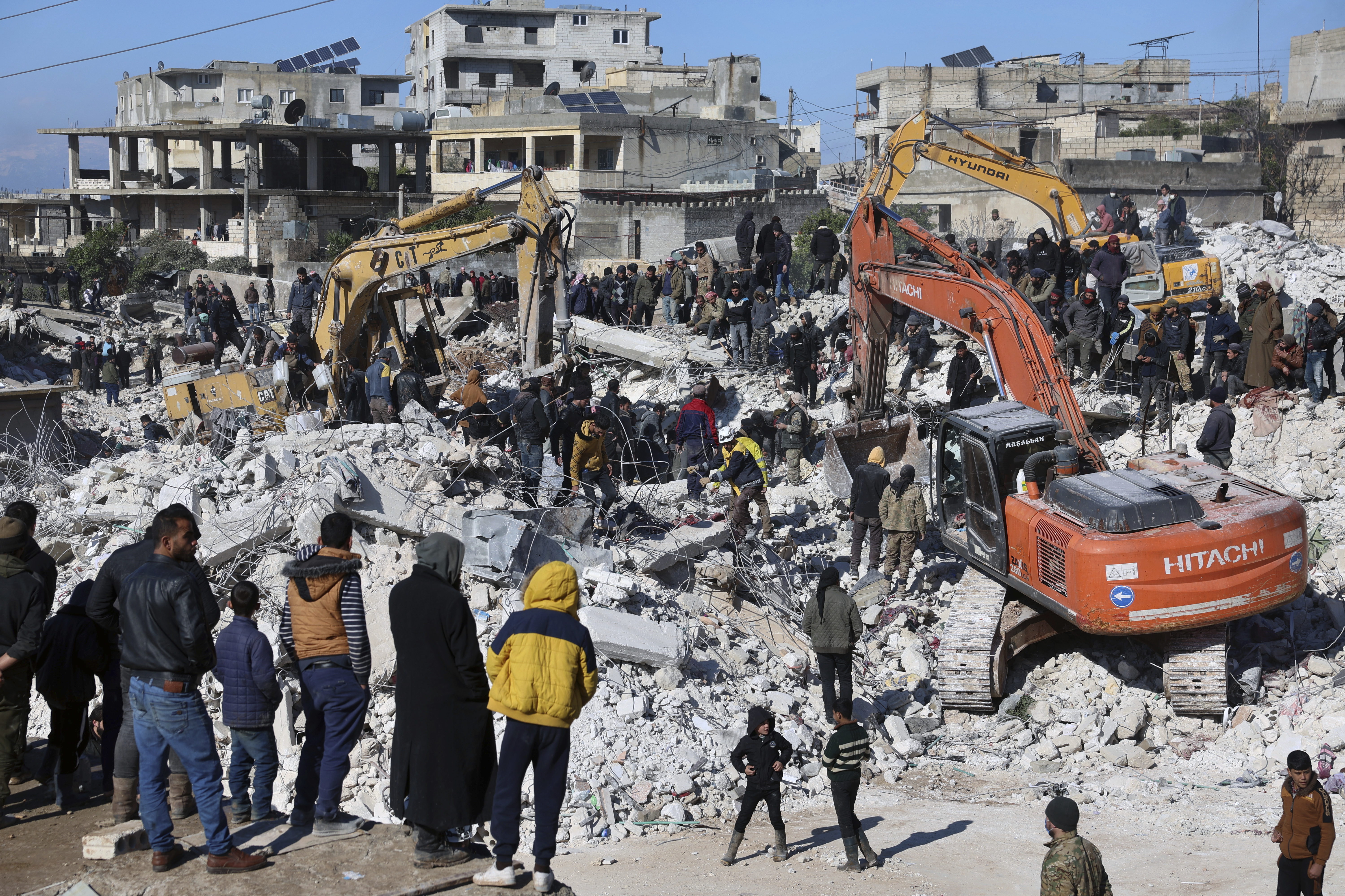 Rescuers and residents search through the rubble of collapsed buildings in the town of Harem near the Turkish border, Idlib province