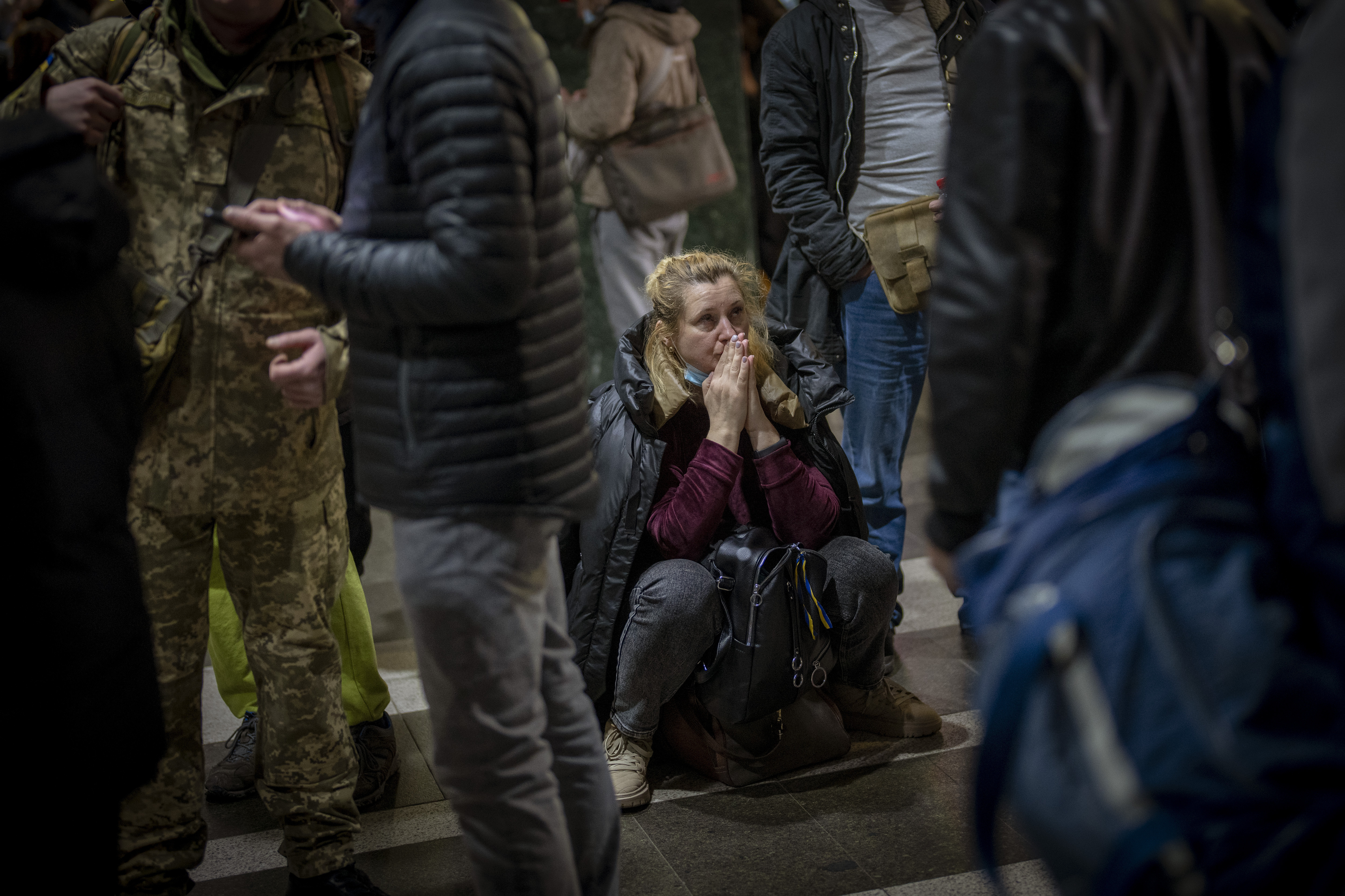 A woman reacts as she waits for a train trying to leave Kyiv