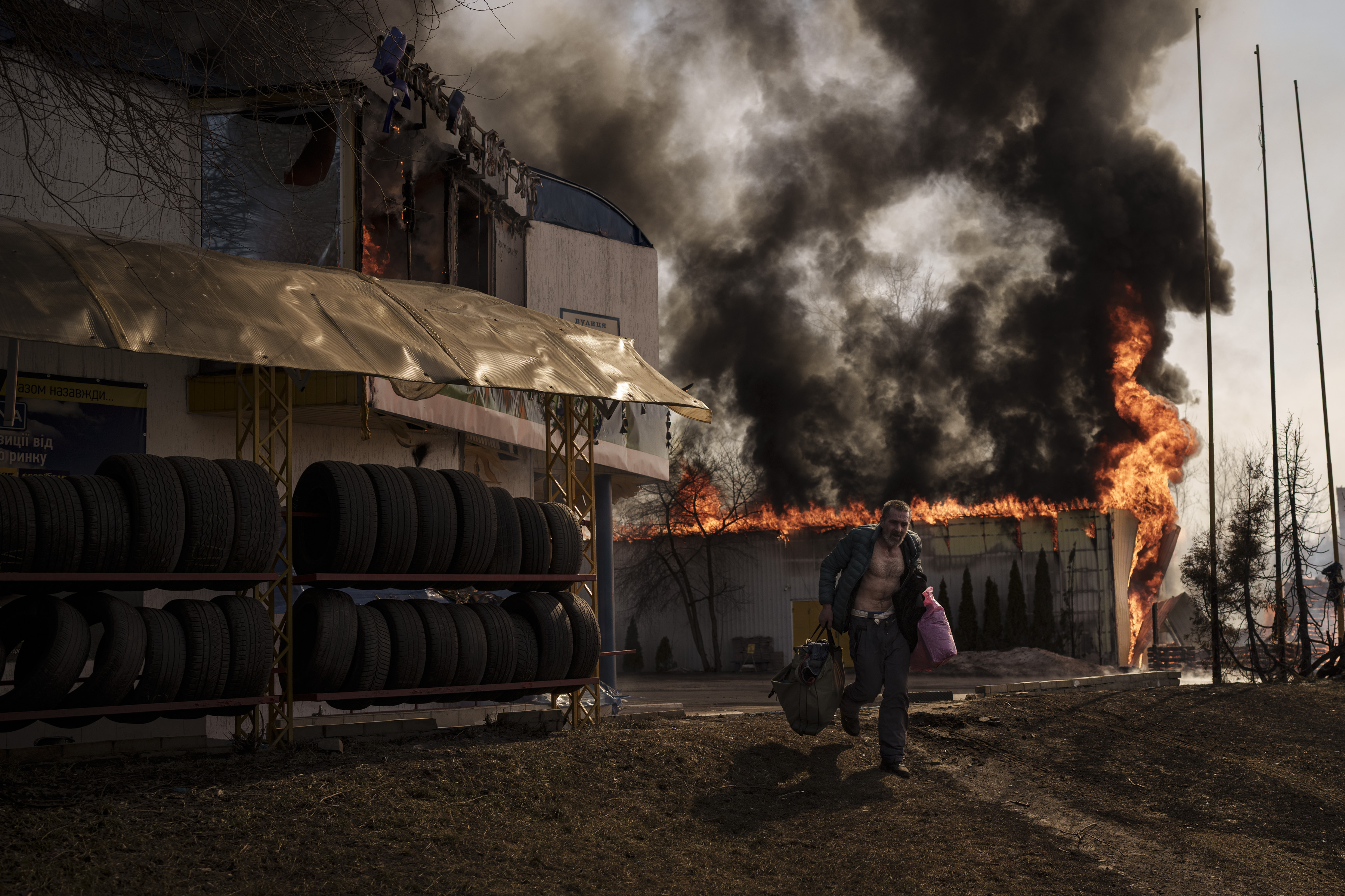 A man runs after recovering items from a burning shop following a Russian attack in Kharkiv