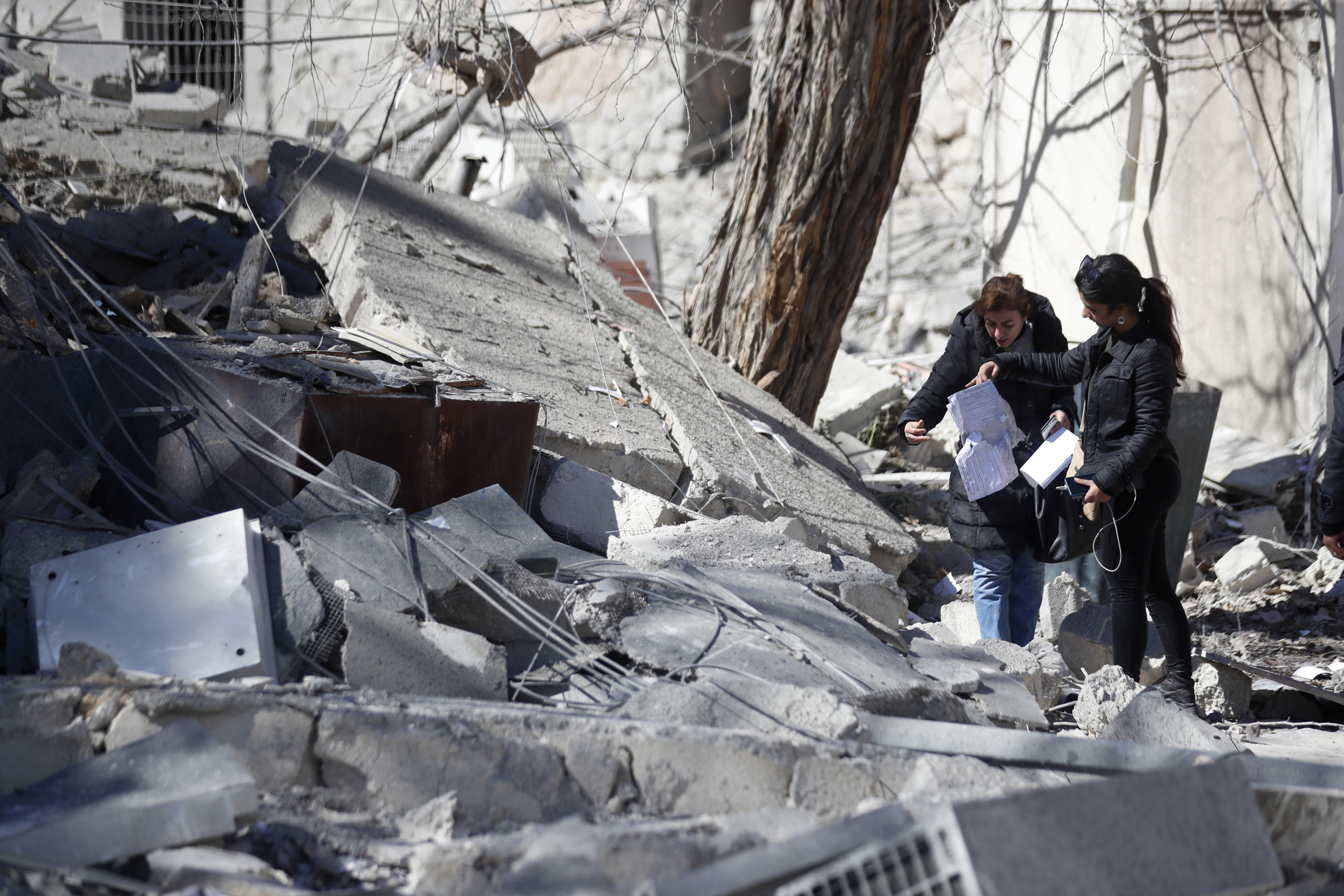 Syrians inspect the damage of a medieval citadel and an applied arts institute house after an early morning Israeli airstrike in the capital city of Damascus