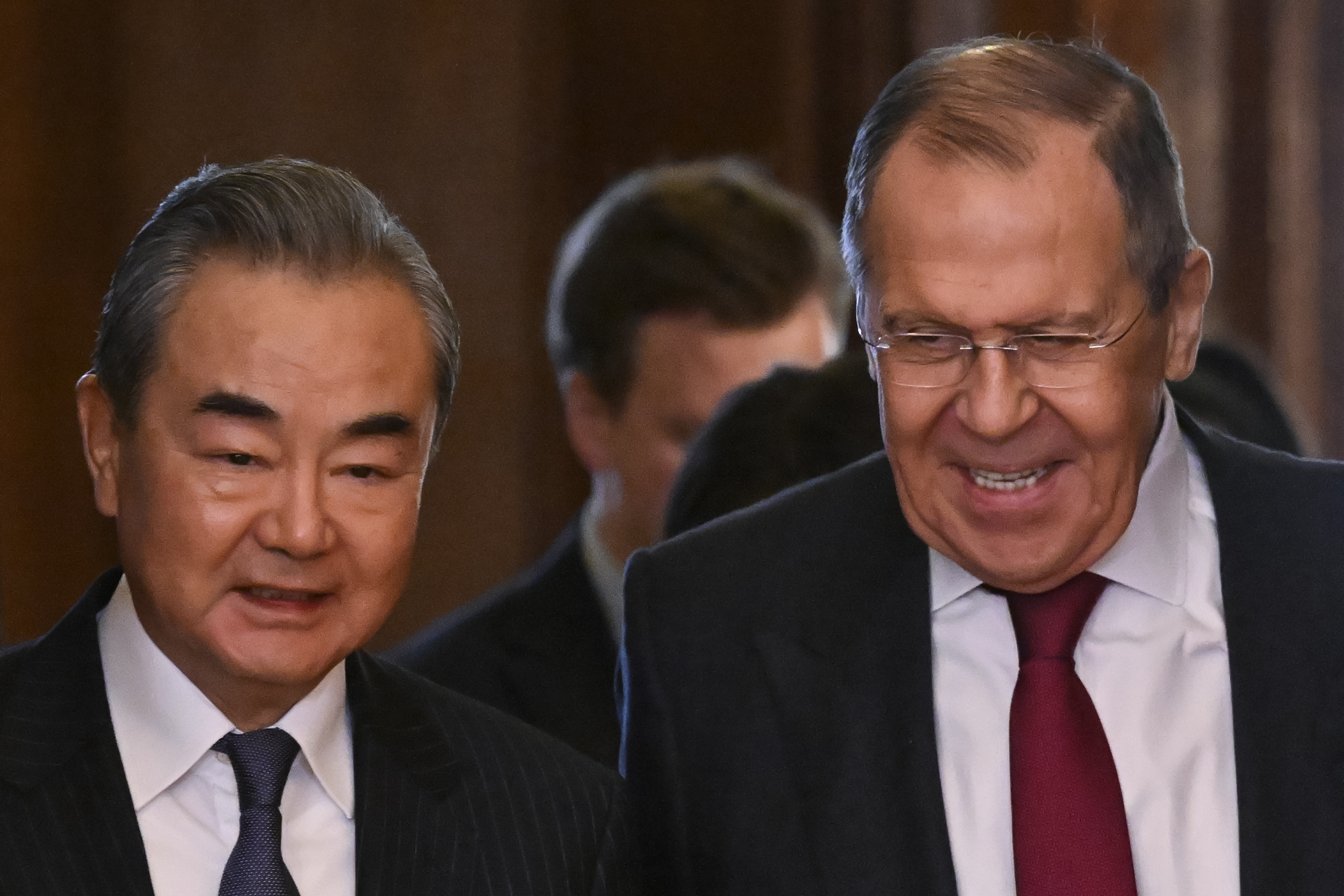 Sergey Lavrov smiling as he shows Wang Yi into a room in the Kremlin. Wang looks very relaxed. Both men are in suits.