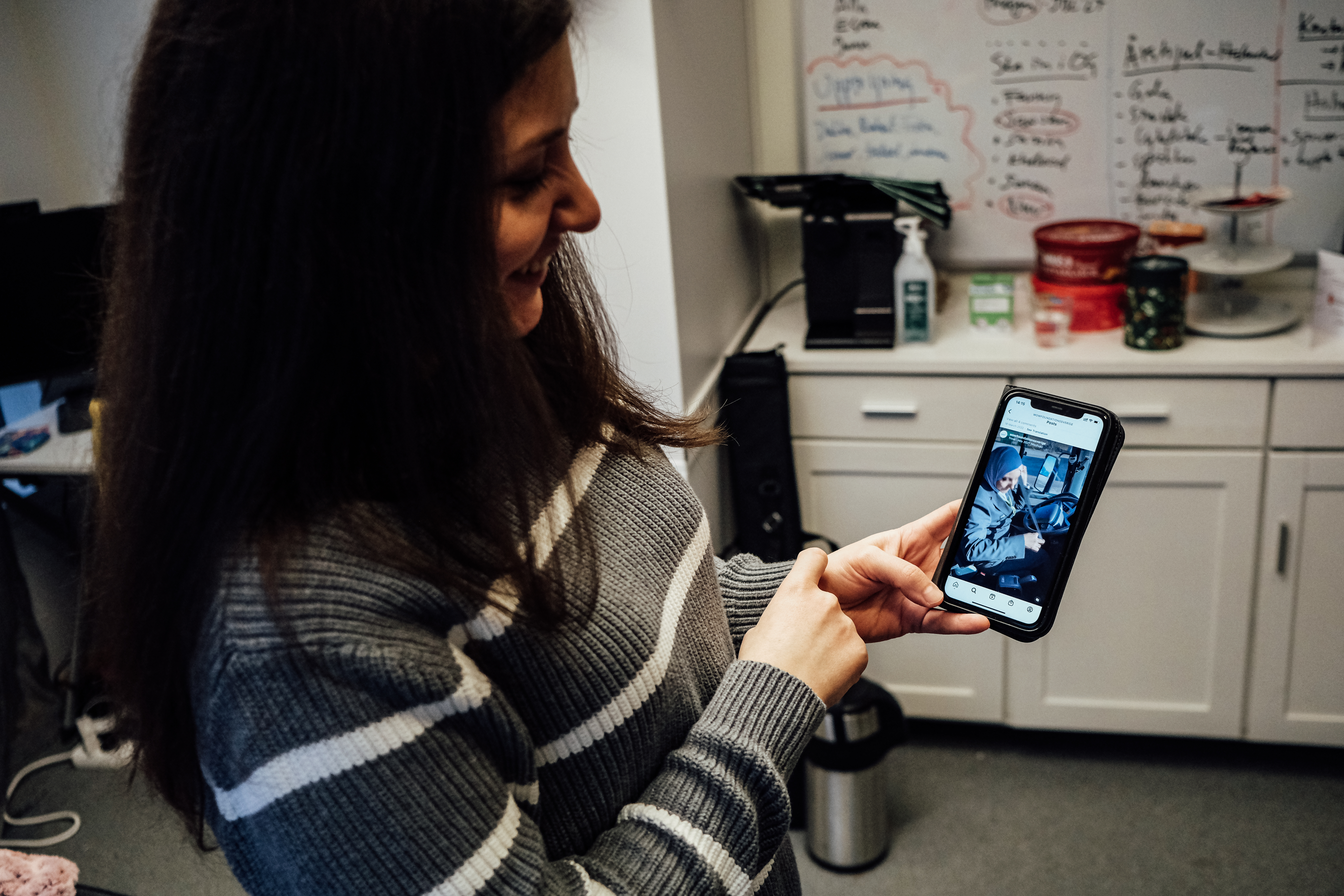 A woman shows her mobile phone to the camera