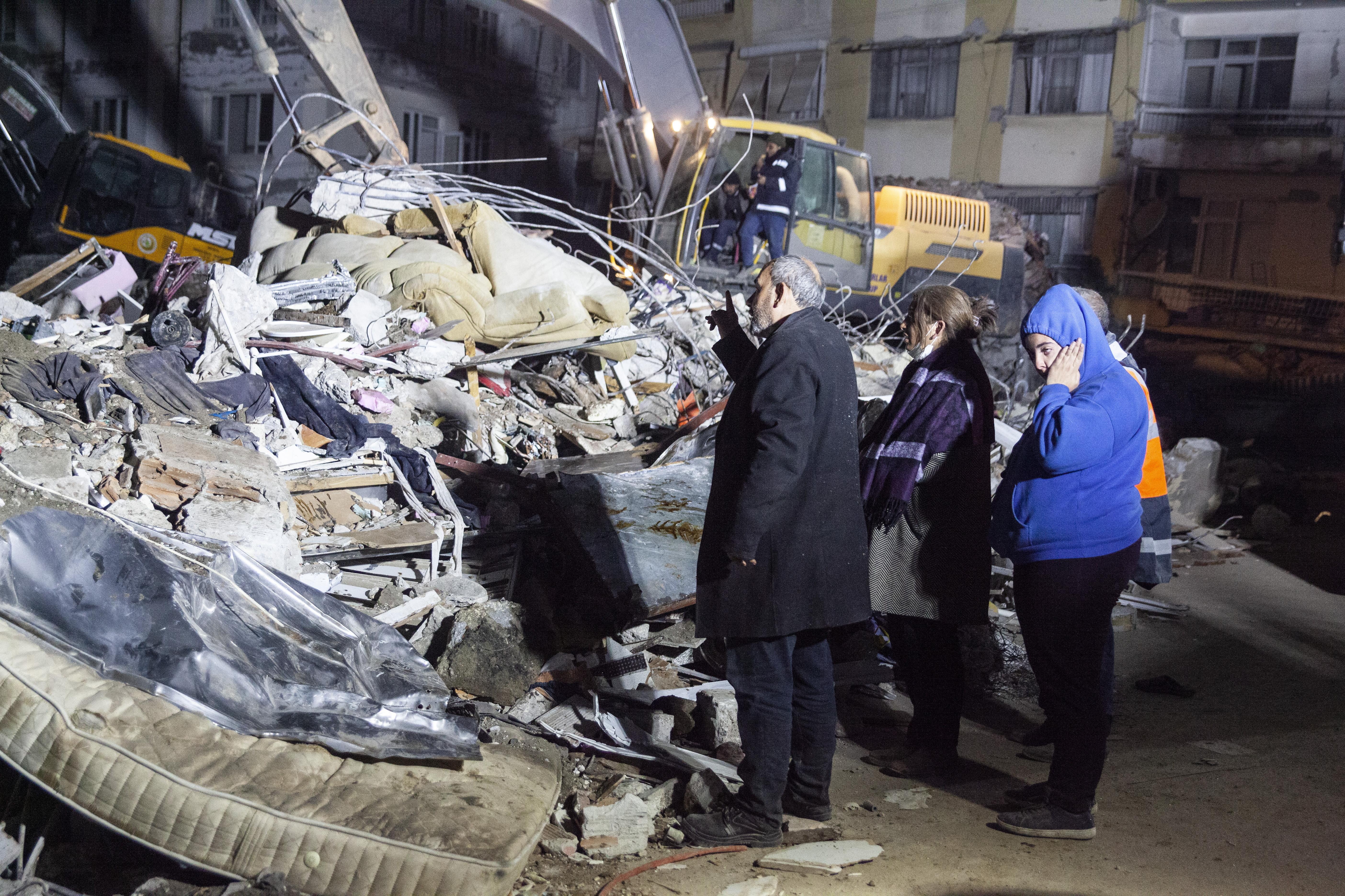Family members wait in front of the destroyed house where their daughter and sister was trapped